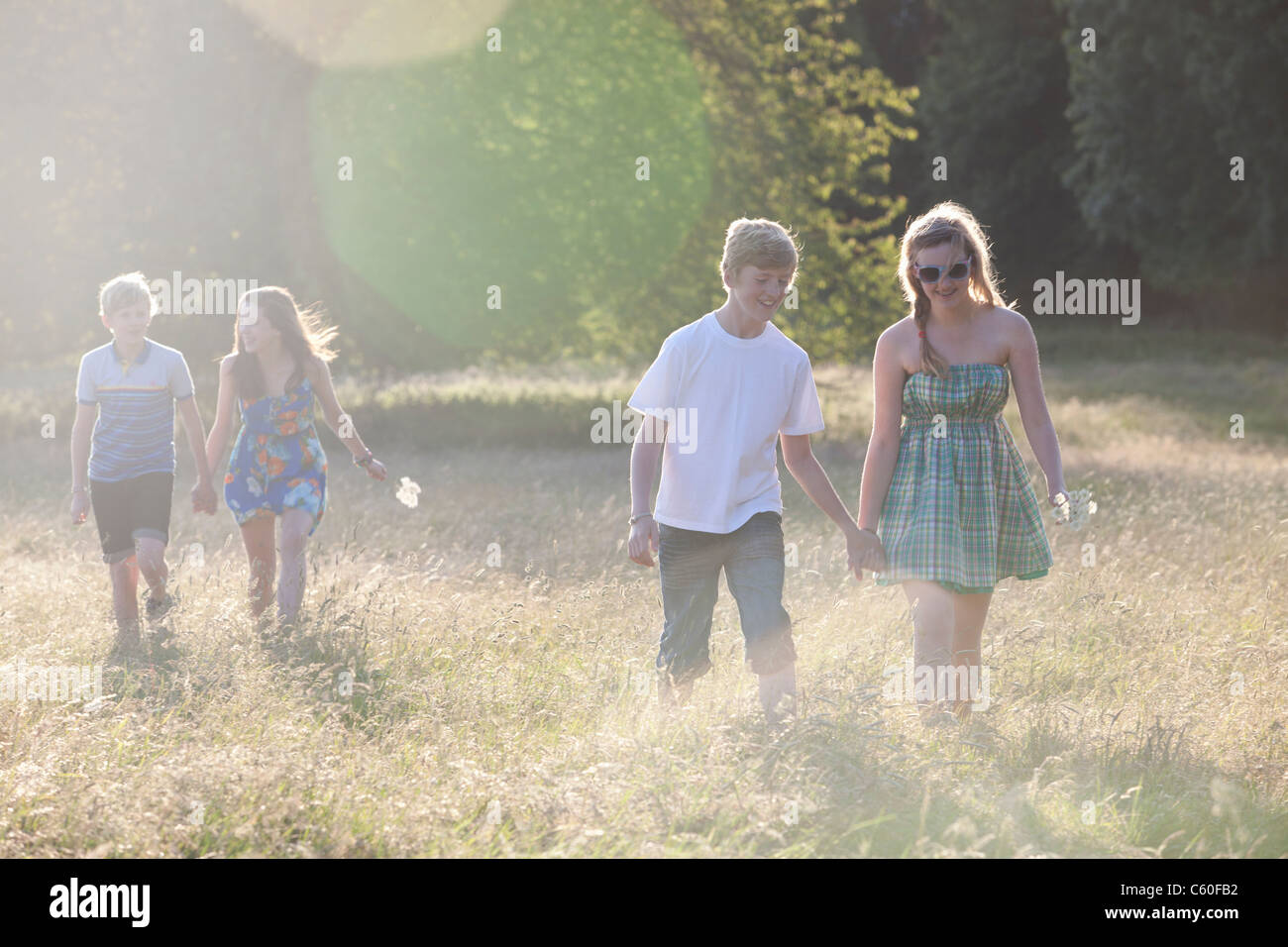 Teenage Paare zu Fuß in Feld Stockfoto