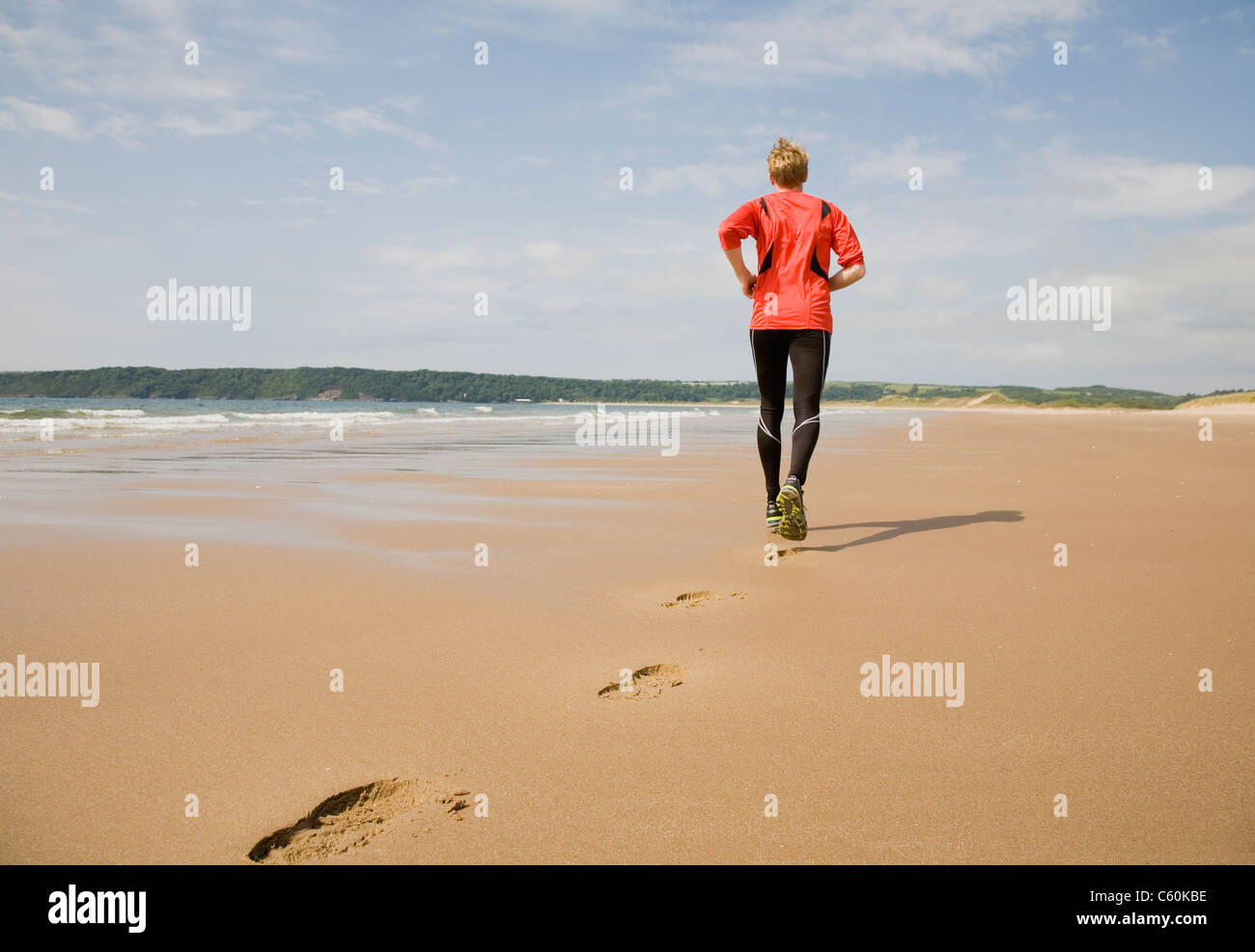 Läufer, die Fußabdrücke am Strand machen Stockfoto