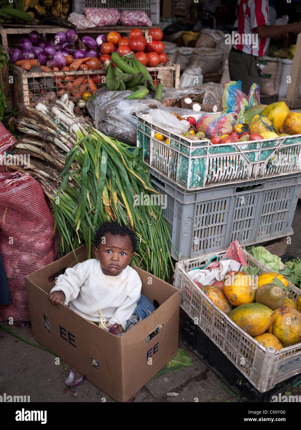 Ein kleiner Junge sitzt in einer Box am Markt. Stockfoto