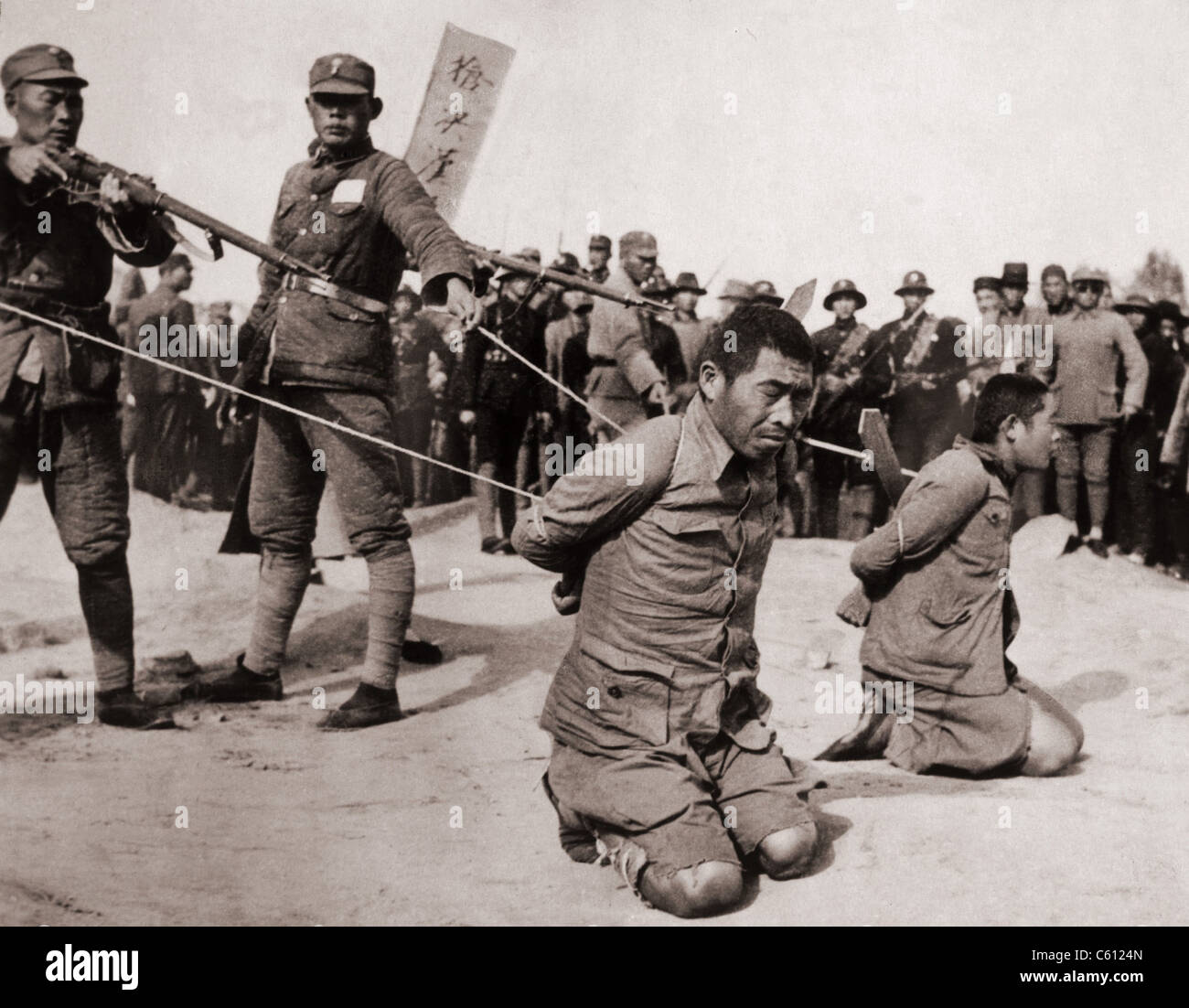 Zwei chinesische Männer knien vor der Ausführung von chinesischen Soldaten. Sino-japanischer Krieg (1937-1945) war ein Kampf gegen die japanische Besatzung sowie ein Bürgerkrieg zwischen Nationalisten und Kommunisten. Stockfoto