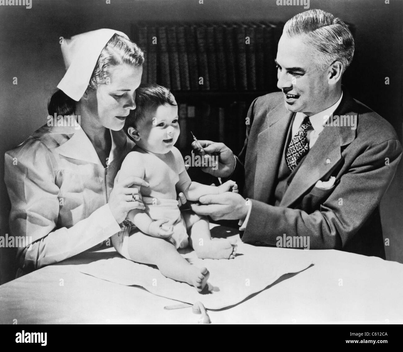 Krankenschwester hält ein Kind wie ein Arzt bereitet sich auf das Kind gegen Influenza zu impfen. 1958 Stockfoto