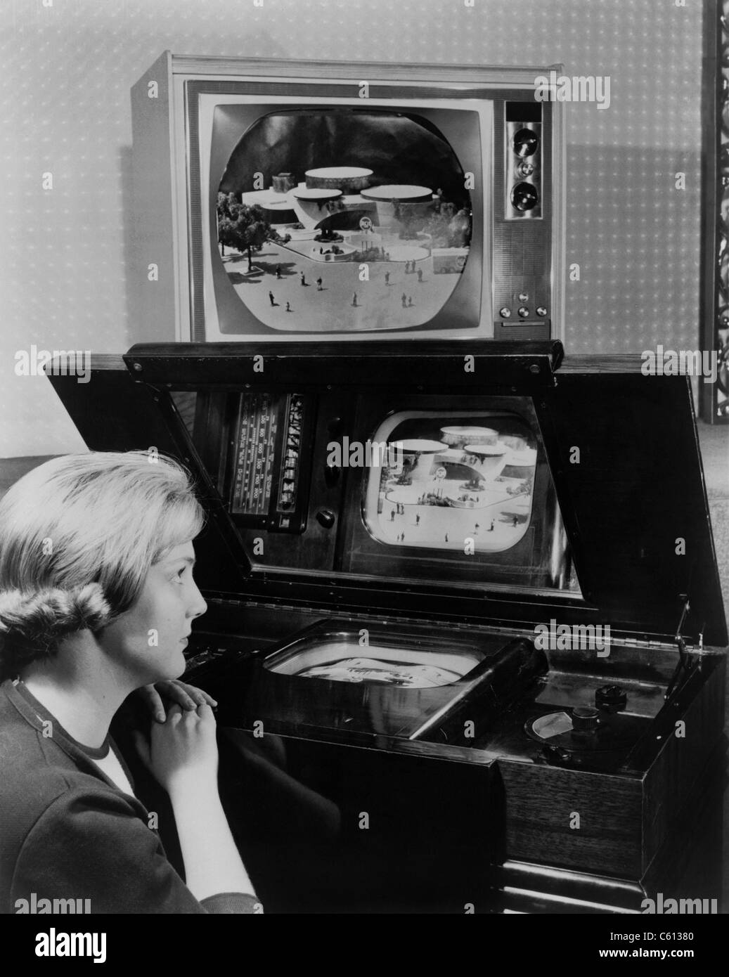 Frau zwei Fernseher betrachten. Man, ähnlich wie ein Satz demonstriert auf der New Yorker Weltausstellung 1939, hat einen kleinen Bildschirm horizontal in einem großen hölzernen Schrank gezwängt und wird von einem reflektierenden Spiegel betrachtet. Die andere, jetzt angezeigt 25 Jahre später bei der 1964 New York World Fair, ist großen abgeschirmten Farb-TV. Stockfoto