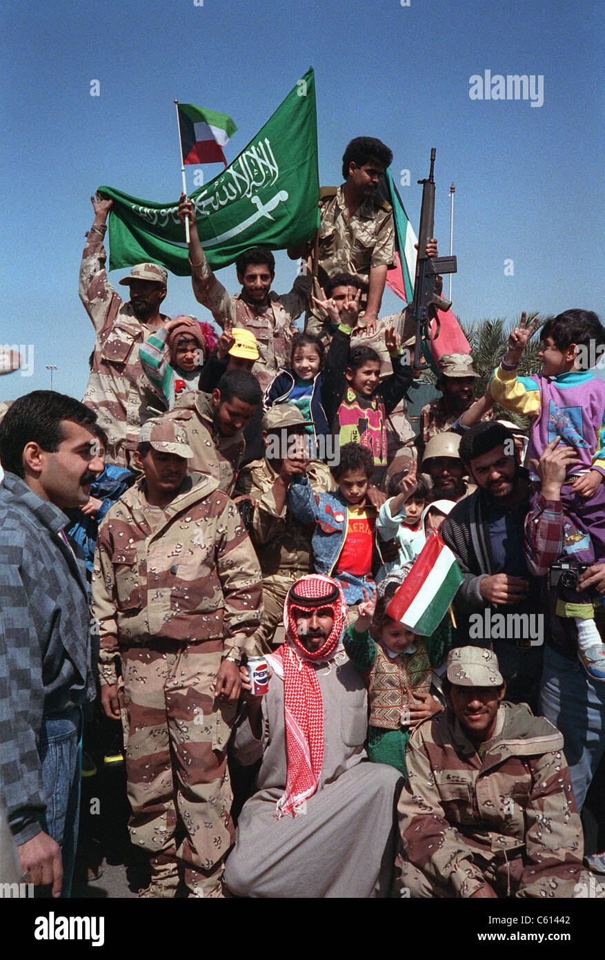 Zivilisten und militärische Koalition Kräfte Welle Kuwait und Saudi-Arabische Flaggen, den Rückzug der irakischen Truppen aus Kuwait als Folge der Operation Desert Storm zu feiern. (BSLOC 2011 3 23) Stockfoto