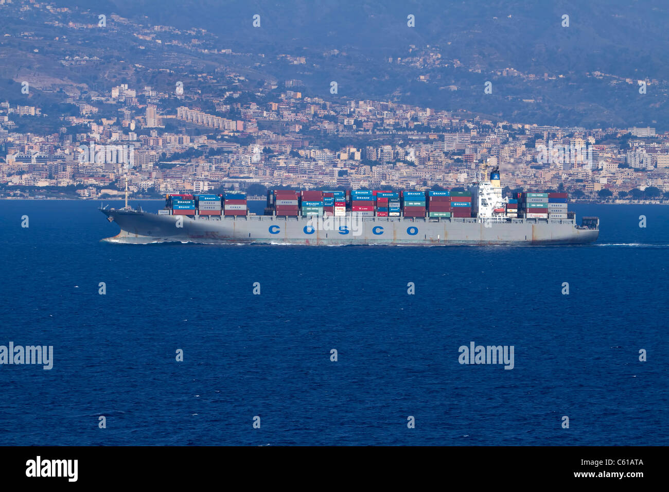 Eine stark belasteter Frachtschiff verlässt Italien für China, mit italienischen Küste im Hintergrund und ein blaues Meer gebunden. Stockfoto
