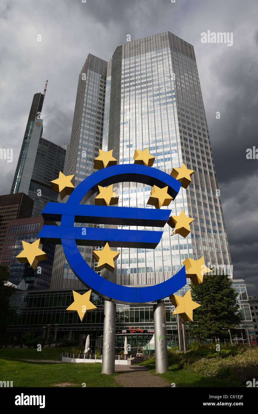 Eine riesige Euro-Symbol steht außerhalb der Europäischen Zentralbank in Frankfurt am Main unter dunklen Wolken. Stockfoto