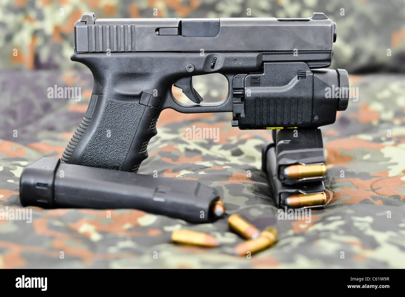 9mm militärische Handfeuerwaffe mit einem taktischen Laser/Licht-Modul auf Tarnung Stockfoto