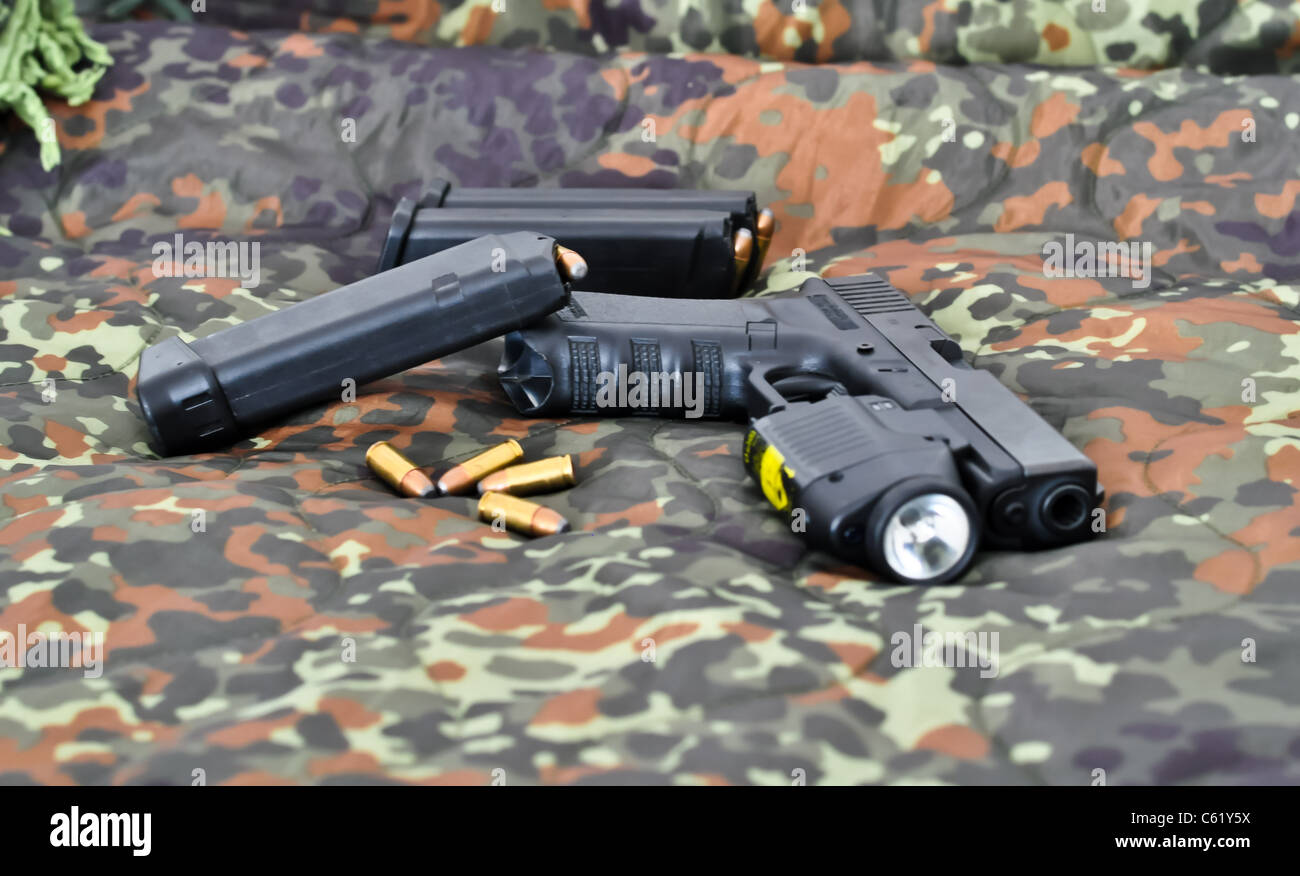 9mm militärische Handfeuerwaffe mit einem taktischen Laser/Licht-Modul auf Tarnung Stockfoto