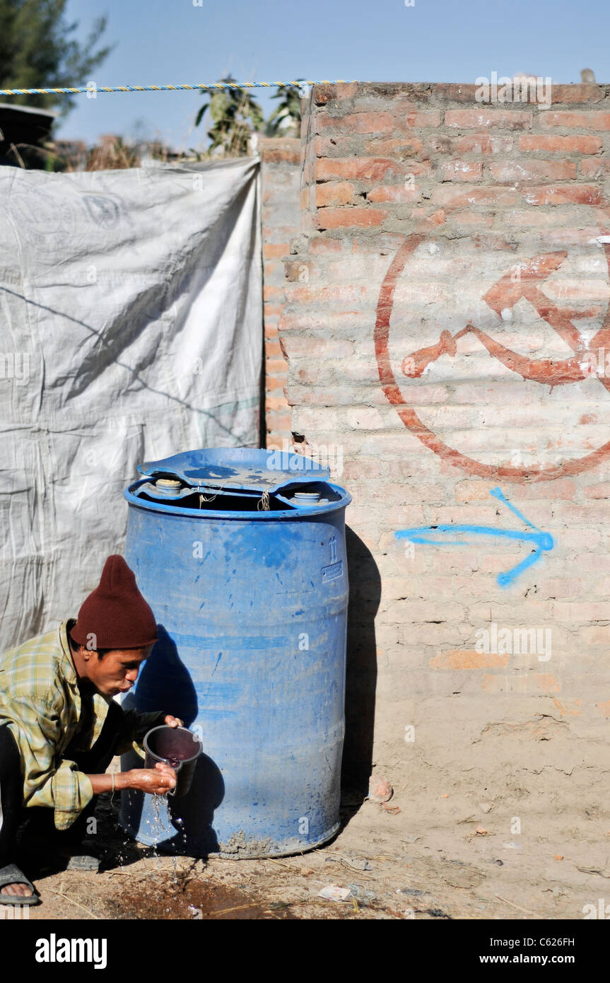 Man Trinkwasser in einem kleinen Dorf im Kathmandu-Tal am Tag der Wahlen Stockfoto