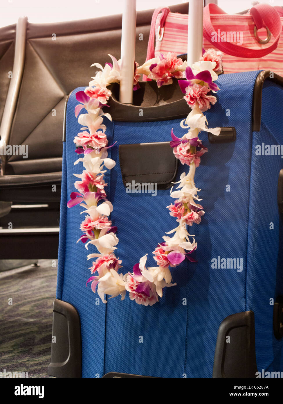 Blume Lei drapiert über Gepäck im Flughafen Stockfoto