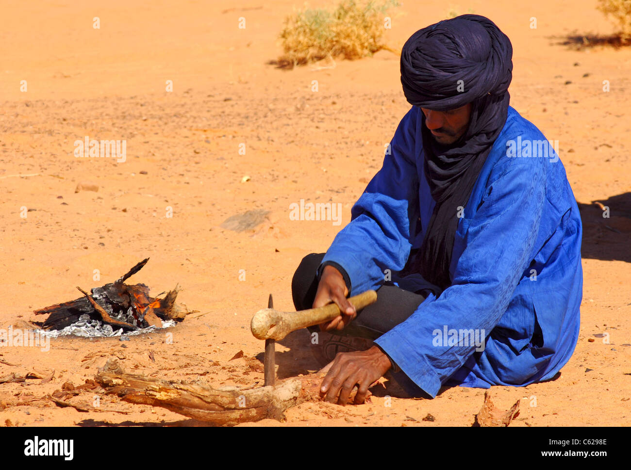 Tuareg-Nomaden ist mit einer einfachen Axt für ein Lagerfeuer, Acacus Berge, Wüste Sahara, Libyen Holz hacken. Stockfoto