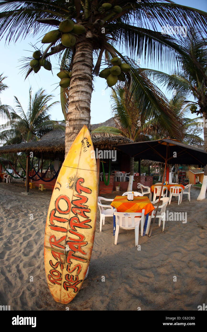 Vordere Strandrestaurant melden Sie auf einem alten gelben Surfbrett in Puerto Escondido. Stockfoto