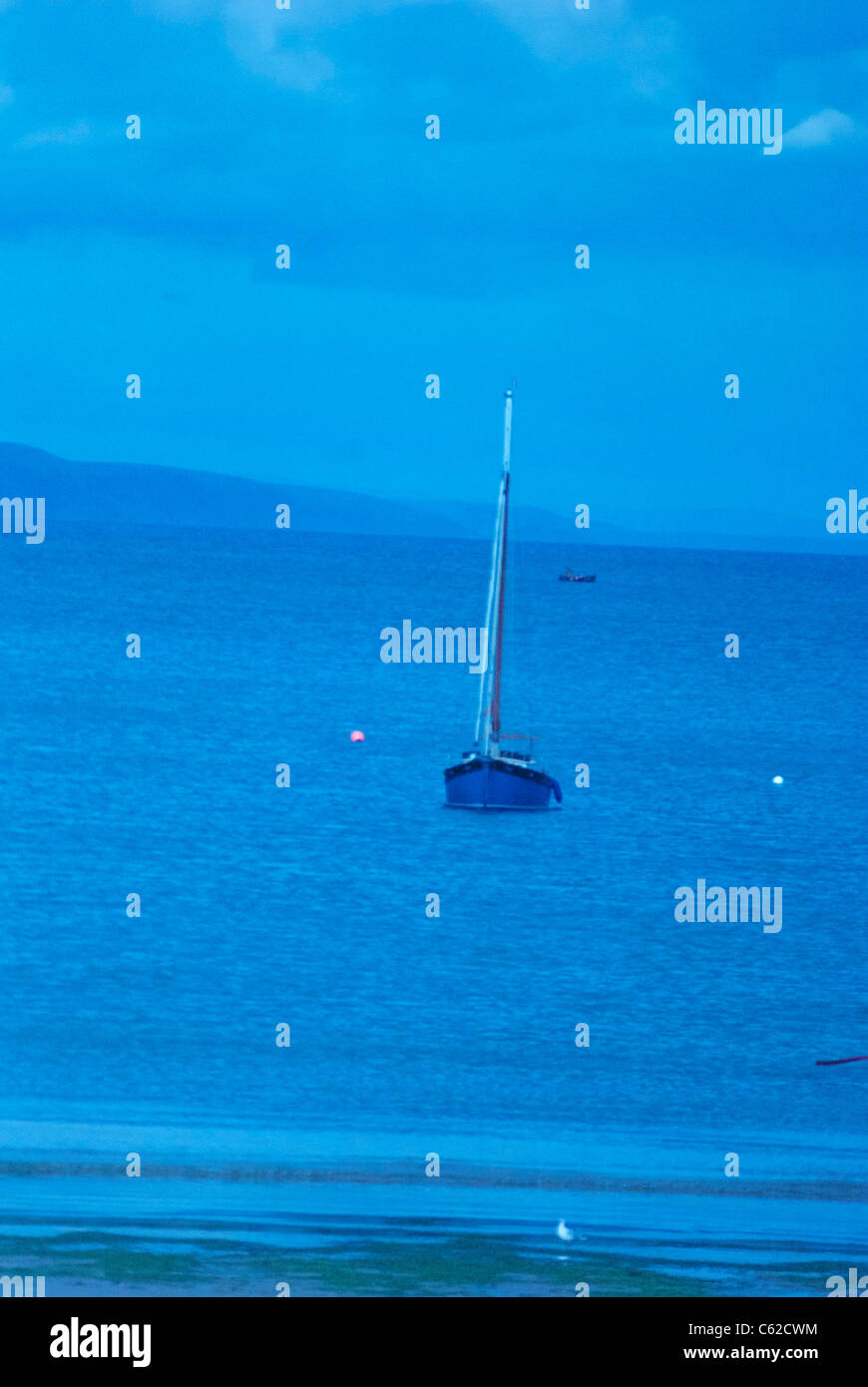 Segelboot in ruhigen blauen Gewässern, die mit Kunstlicht einstellen Stockfoto
