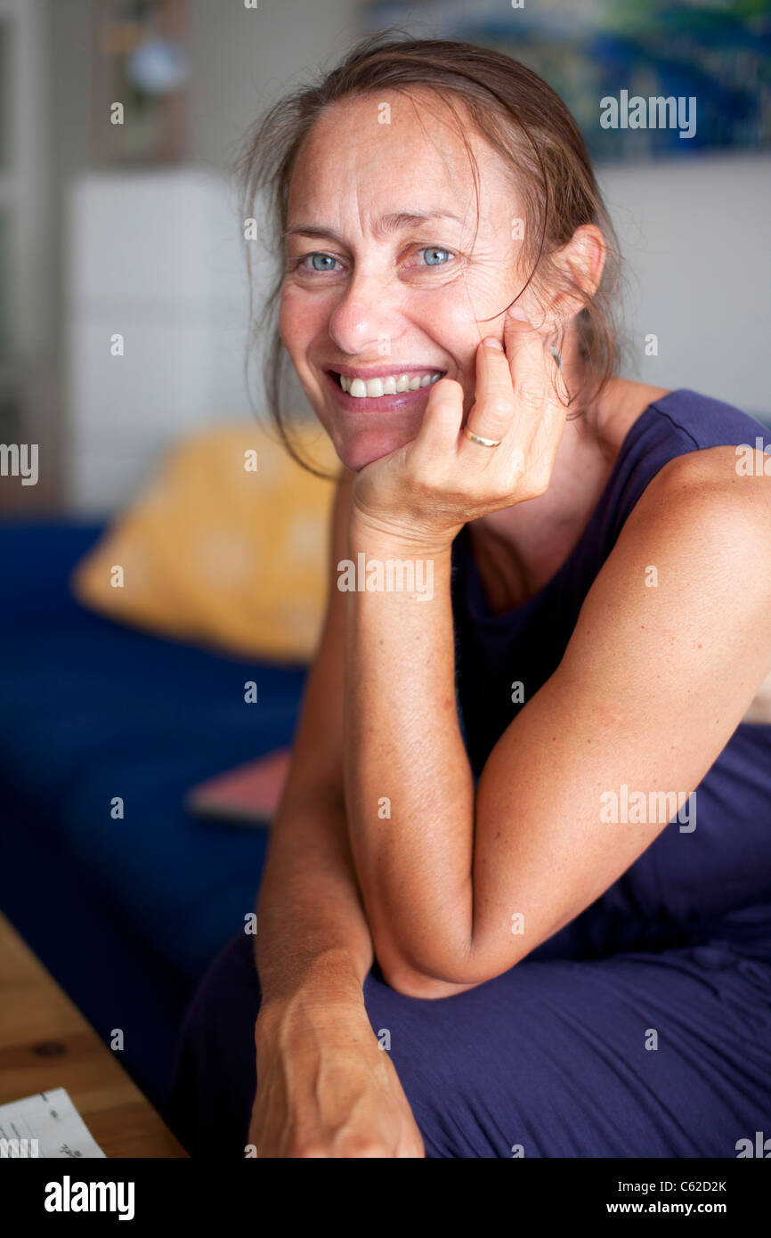 Frau 40er auf Sofa zu Hause sitzen und Lächeln Stockfoto