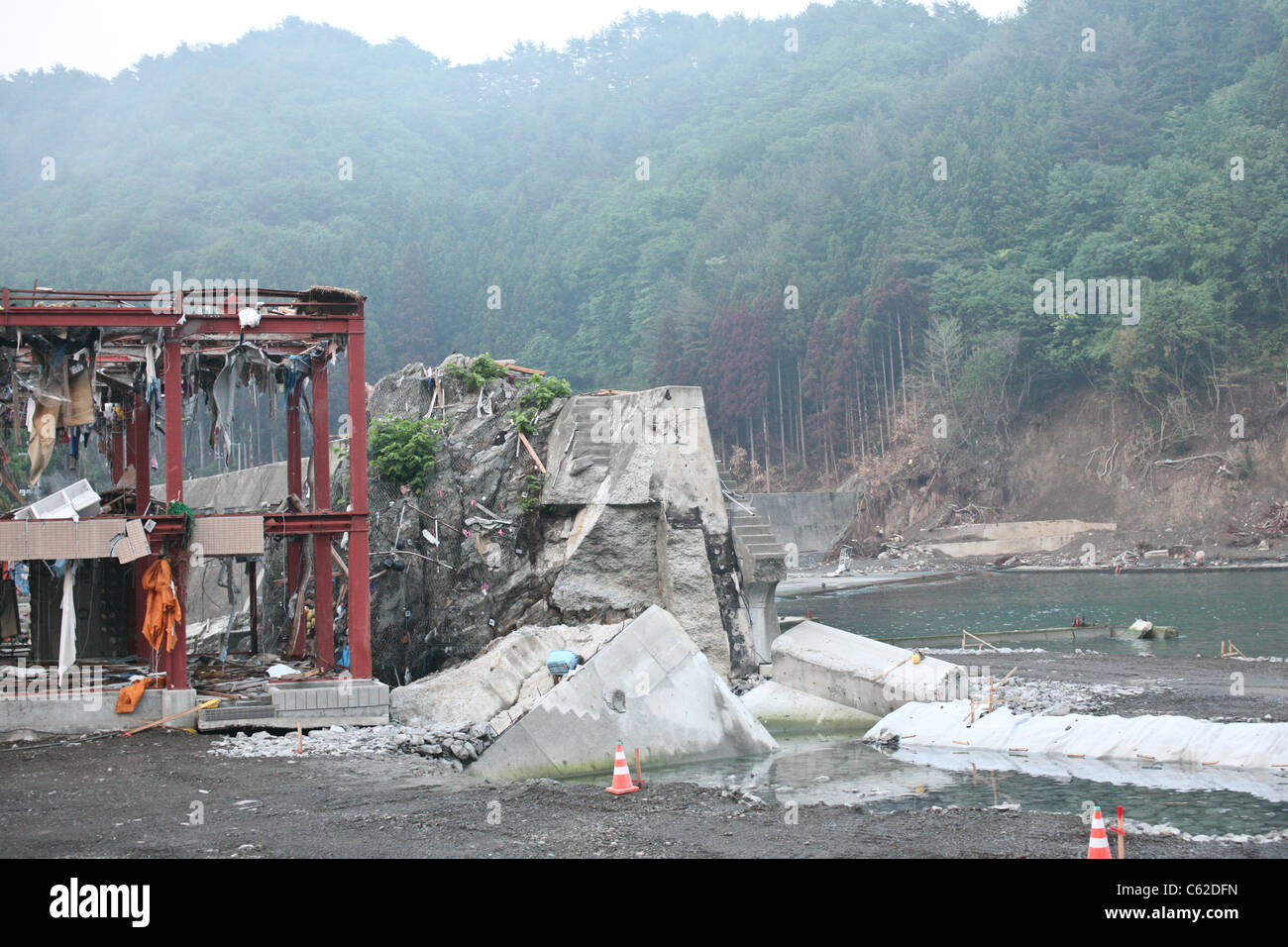 Eine Tsunami Wand konnte nicht in der Nähe von Kesennuma, Japan und die Gebäude und das Dorf dahinter wurden zerstört. Stockfoto