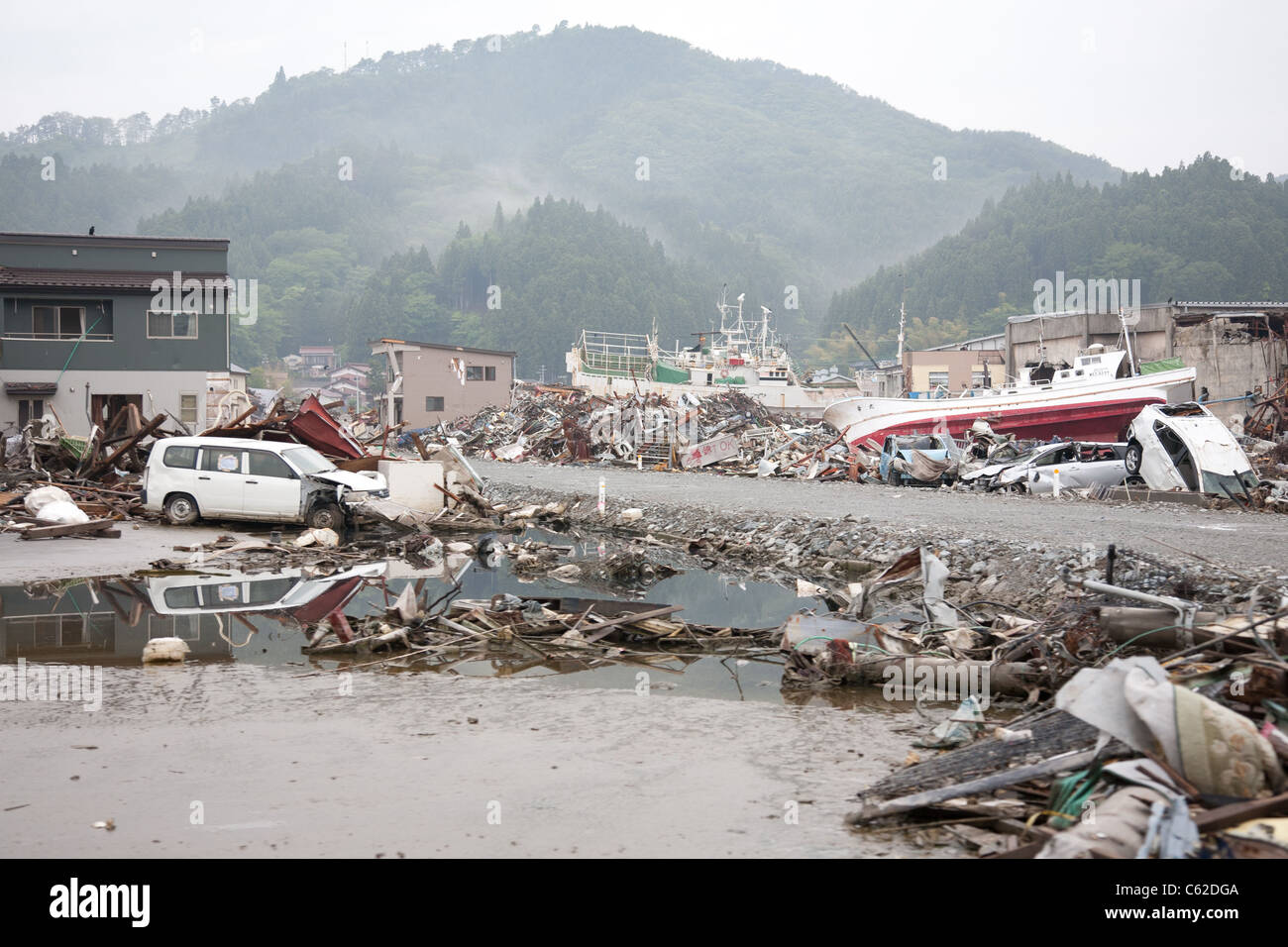Wracks von Schiffen und Autos sitzen neben einer geräumten Straße 3 Monate nach dem Erdbeben und Tsunami in Japan Kesennuma. Stockfoto