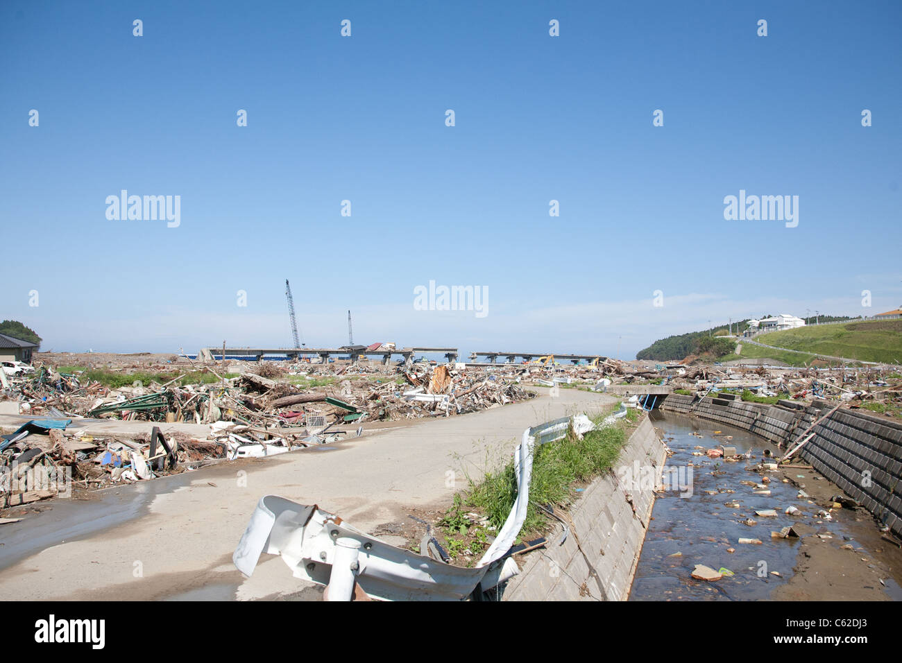 Ein Bahngleis wird zerstört und die Dächer der Häuser sitzen an der Spitze mit einem Fluss im Vordergrund mit Müll übersät ist. Stockfoto