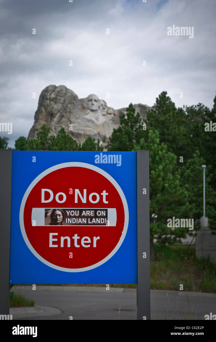 Betreten Sie kein Schild auf einem Parkplatz zum Mount Rushmore mit einem Aufkleber, Sie sind auf indischem Land mit Präsidenten Köpfen im Hintergrund Hi-res Stockfoto