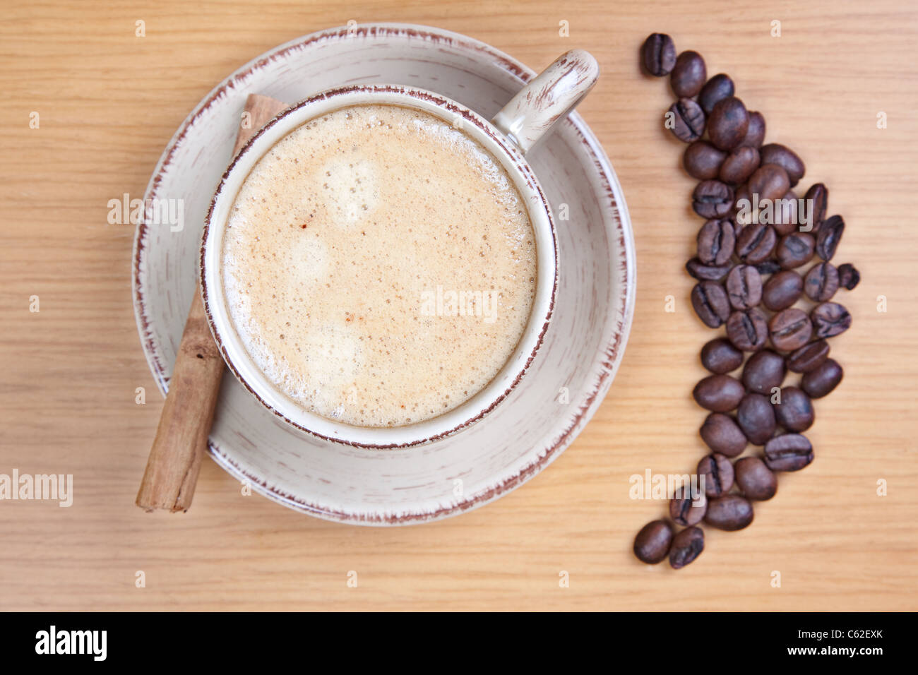 Kaffeetasse am Tisch mit einem Kaffee-Bohnen. Der Schwerpunkt liegt in der Creme. Stockfoto