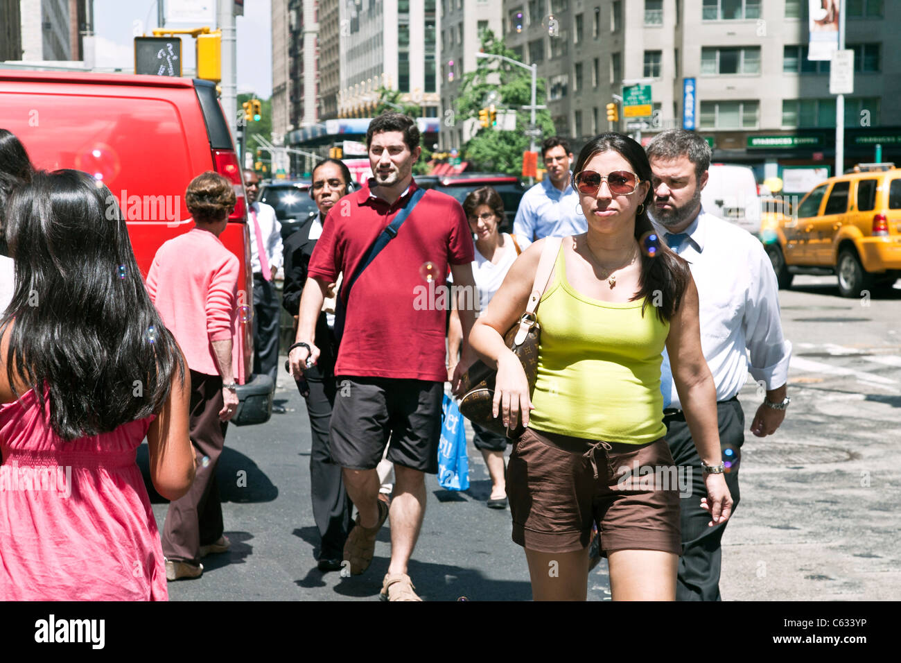 gemischtes Publikum Fußgänger gekleidet für einen heißen Sommertag überqueren 57th Street bei Sixth Avenue in Midtown Manhattan New York City Stockfoto
