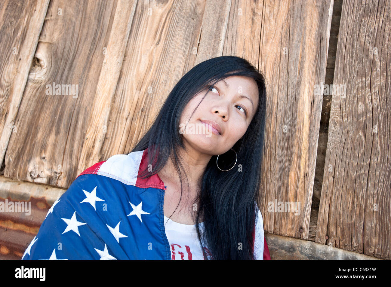 Schöne patriotischen asiatische Frau eingewickelt in eine amerikanische Flagge denken über ihre Freiheit. Stockfoto