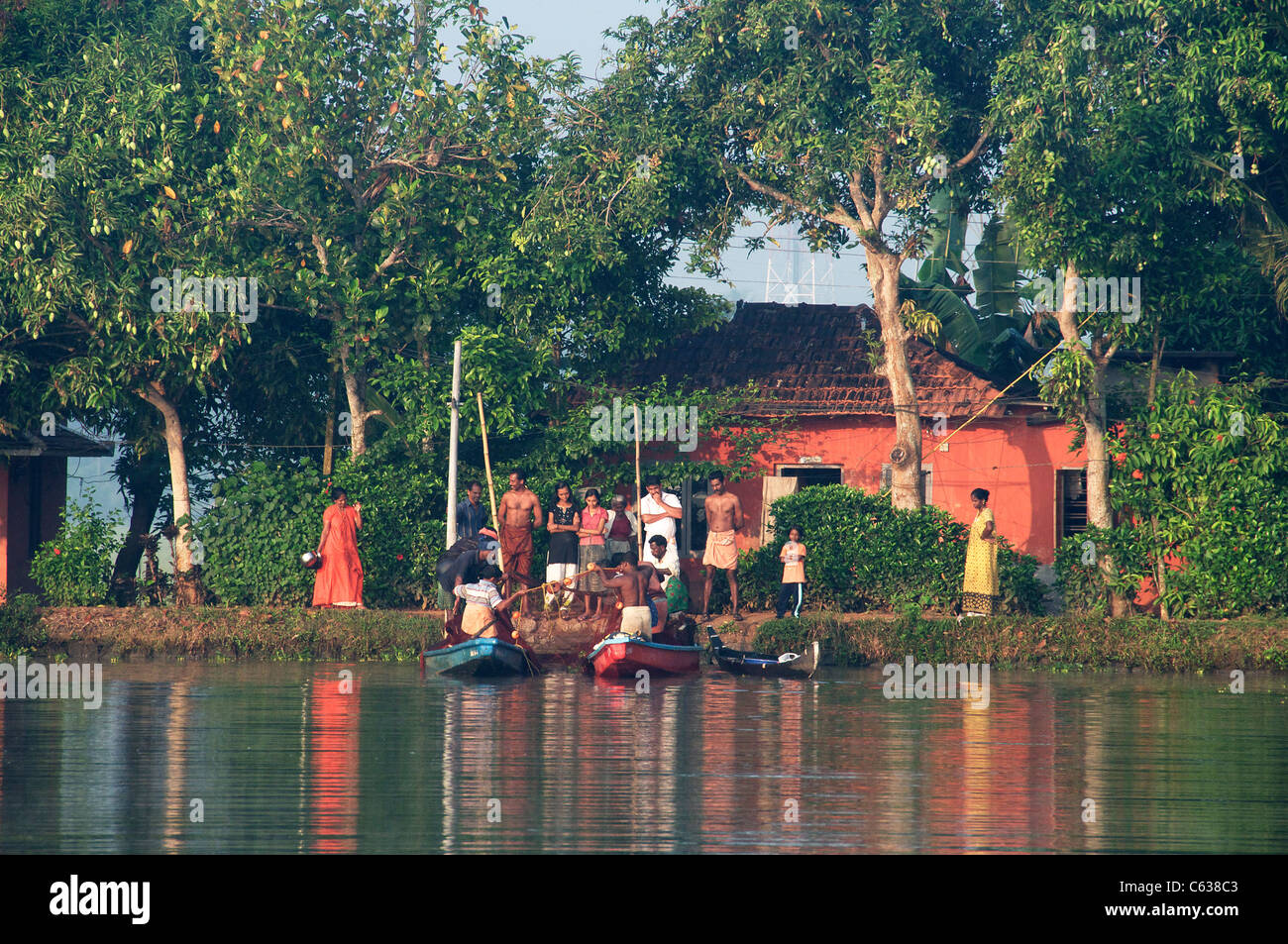 Dorfbewohner beobachten Fischer in den frühen Morgenstunden Licht Backwaters Kerala Süd-Indien Stockfoto