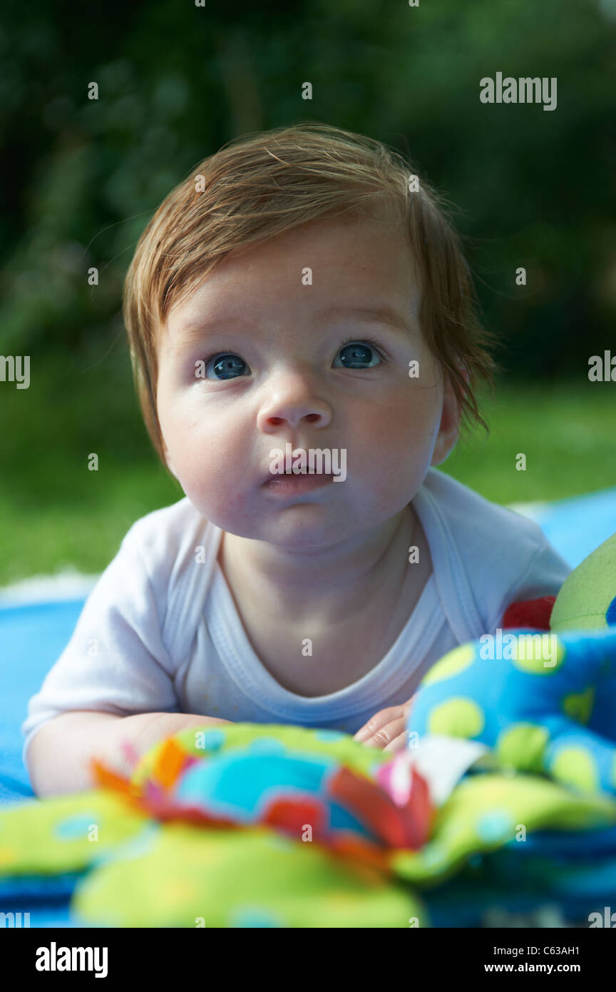 Kleines Mädchen auf blaue Decke Gras außen liegend Stockfoto