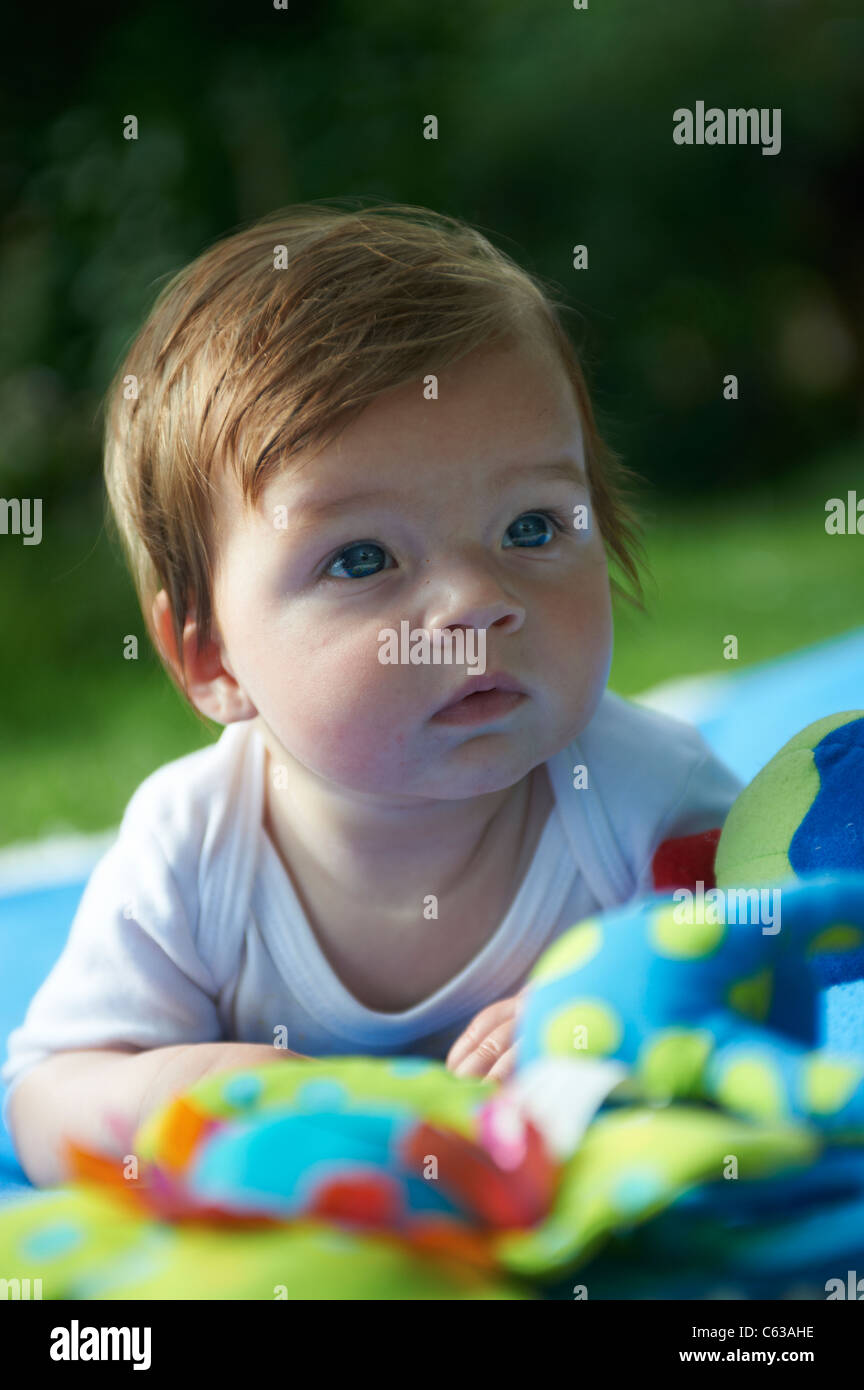 Kleines Mädchen auf blaue Decke Gras außen liegend Stockfoto