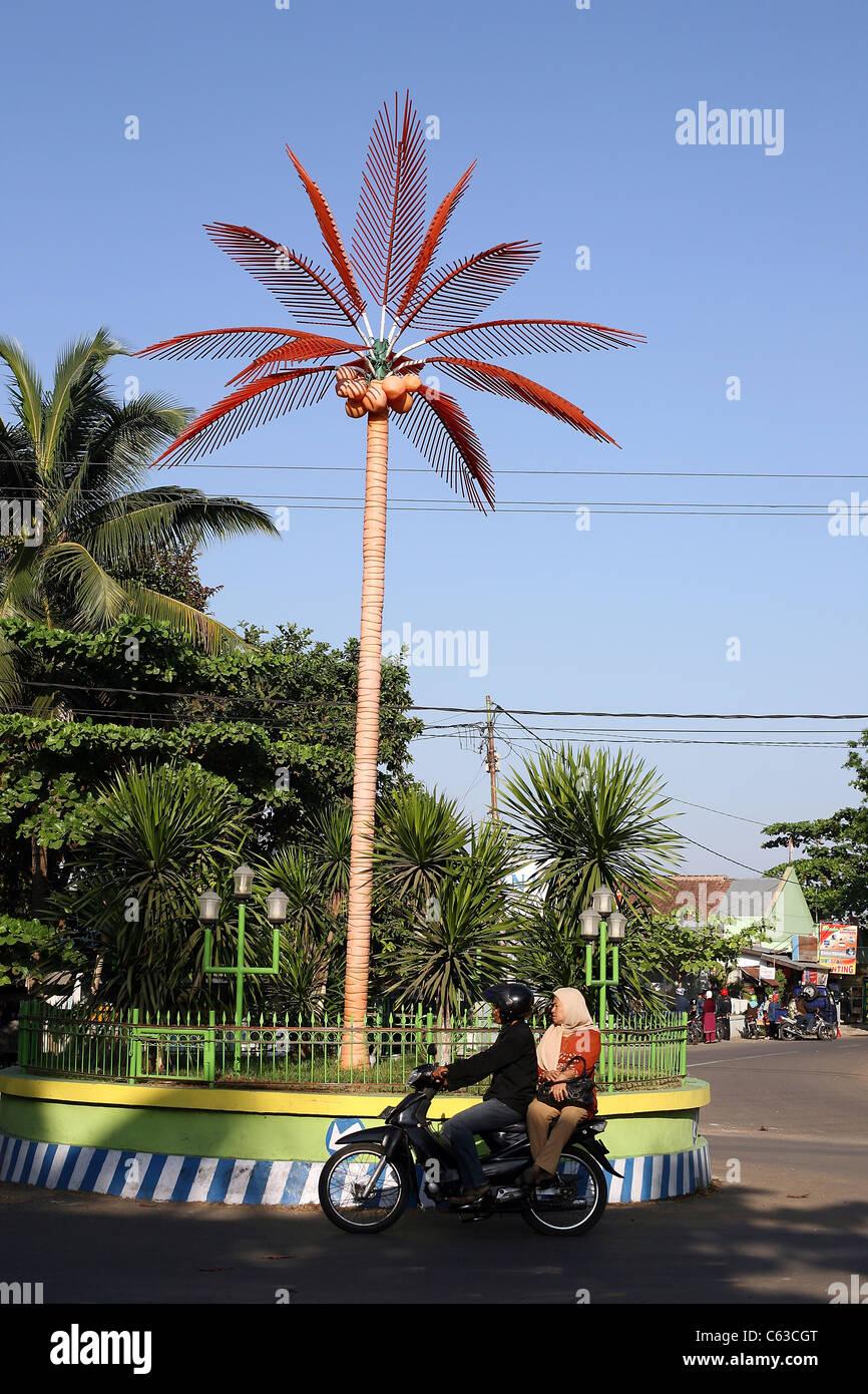 Motorrad geht einen Kreisverkehr mit einer künstlichen Kokospalme Stockfoto