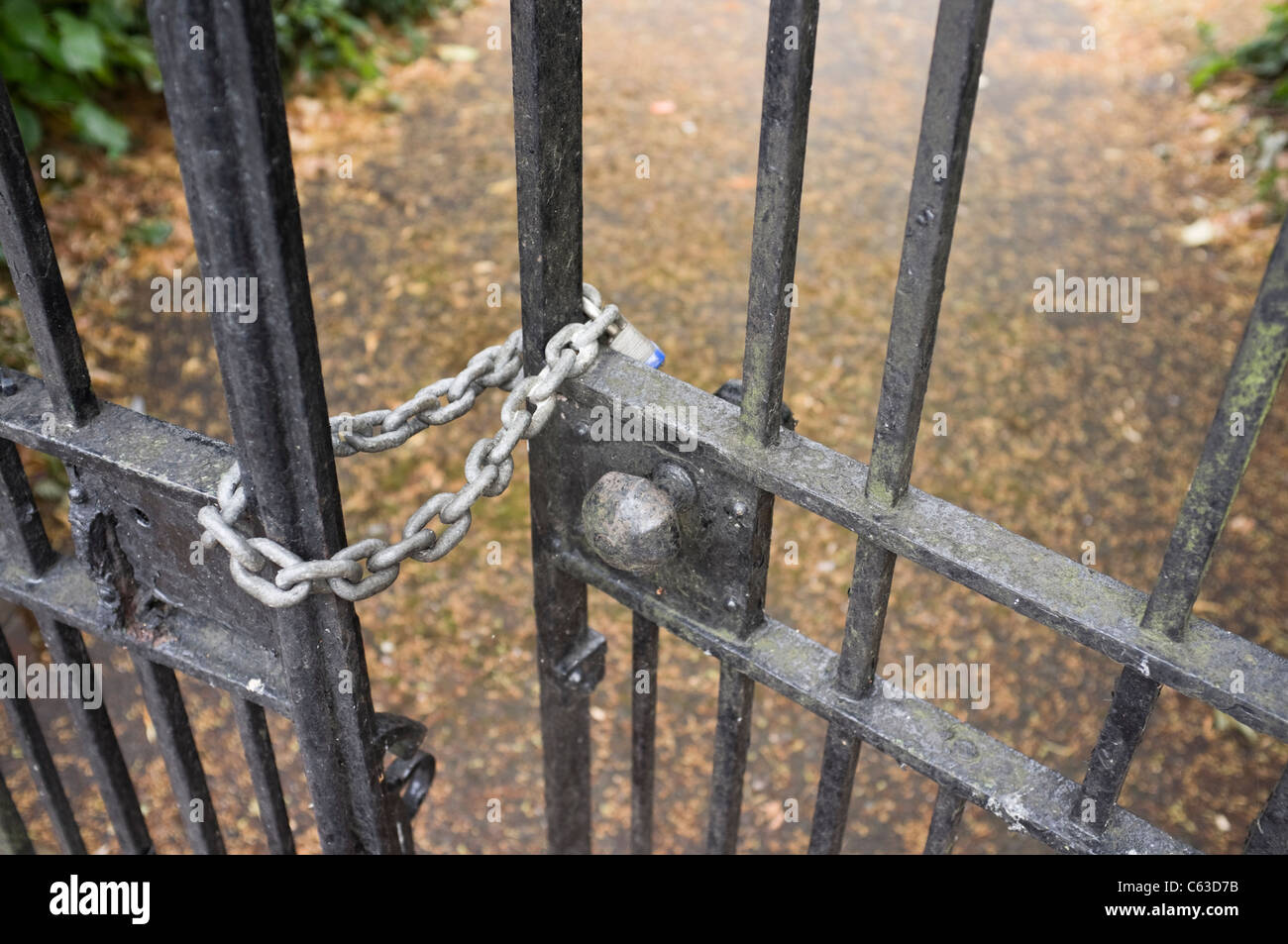 England, UK, Großbritannien. Vorhängeschloss an einer Kette sperren schmiedeeisernen Toren am Eingang zu einer Schule in Nahaufnahme Stockfoto