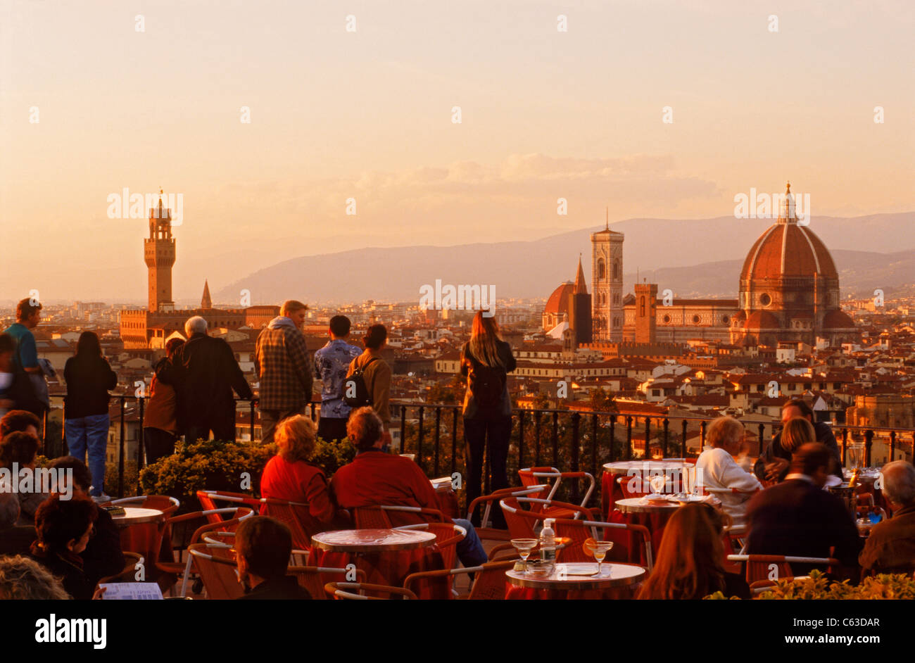 Menschen und Tabellen in Straßencafé am Piazzale Michelangelo über dem Fluss Arno und Florenz im Abendlicht Stockfoto