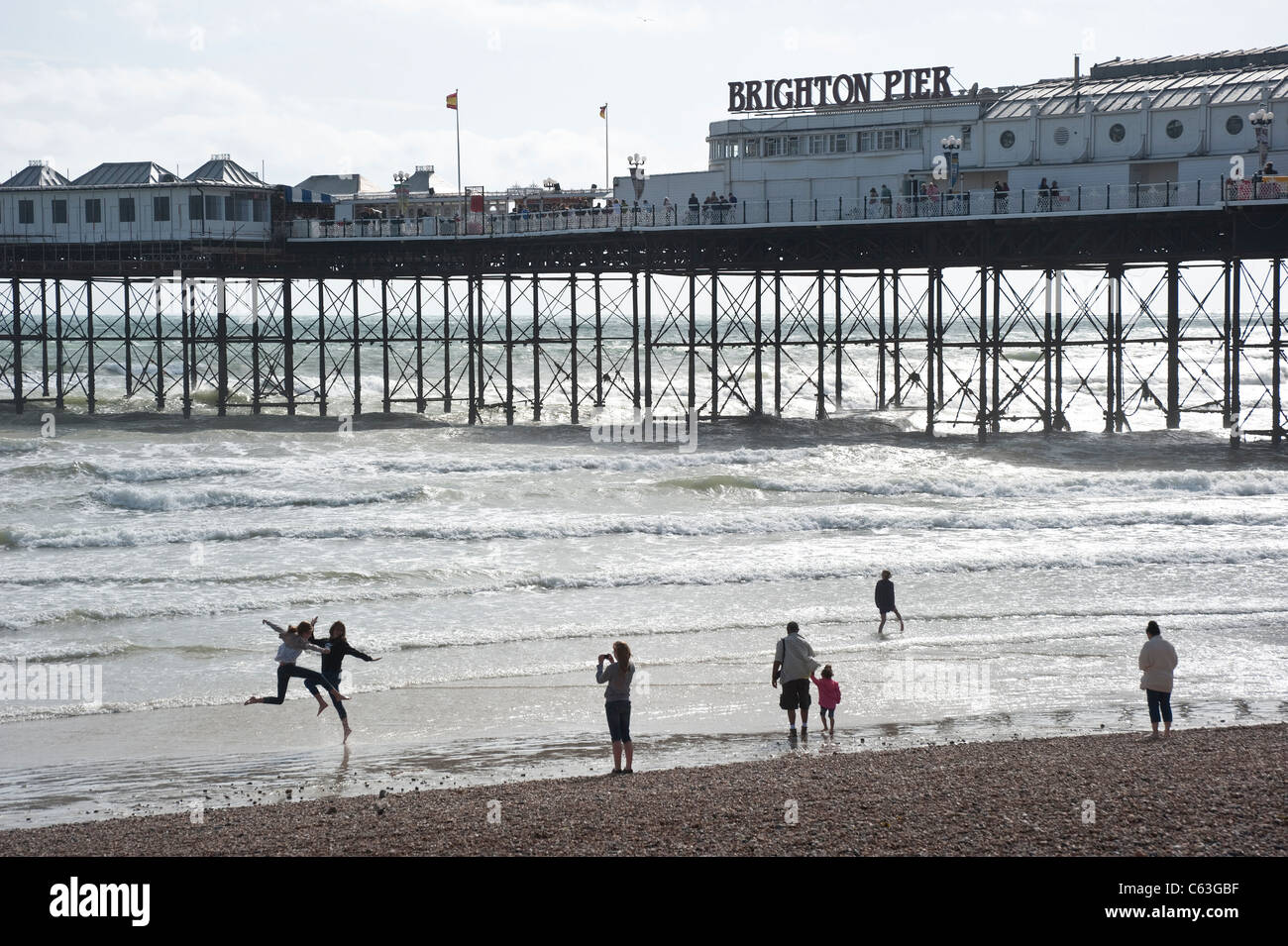 Brighton Pier mit Menschen spielen in den Wellen Stockfoto