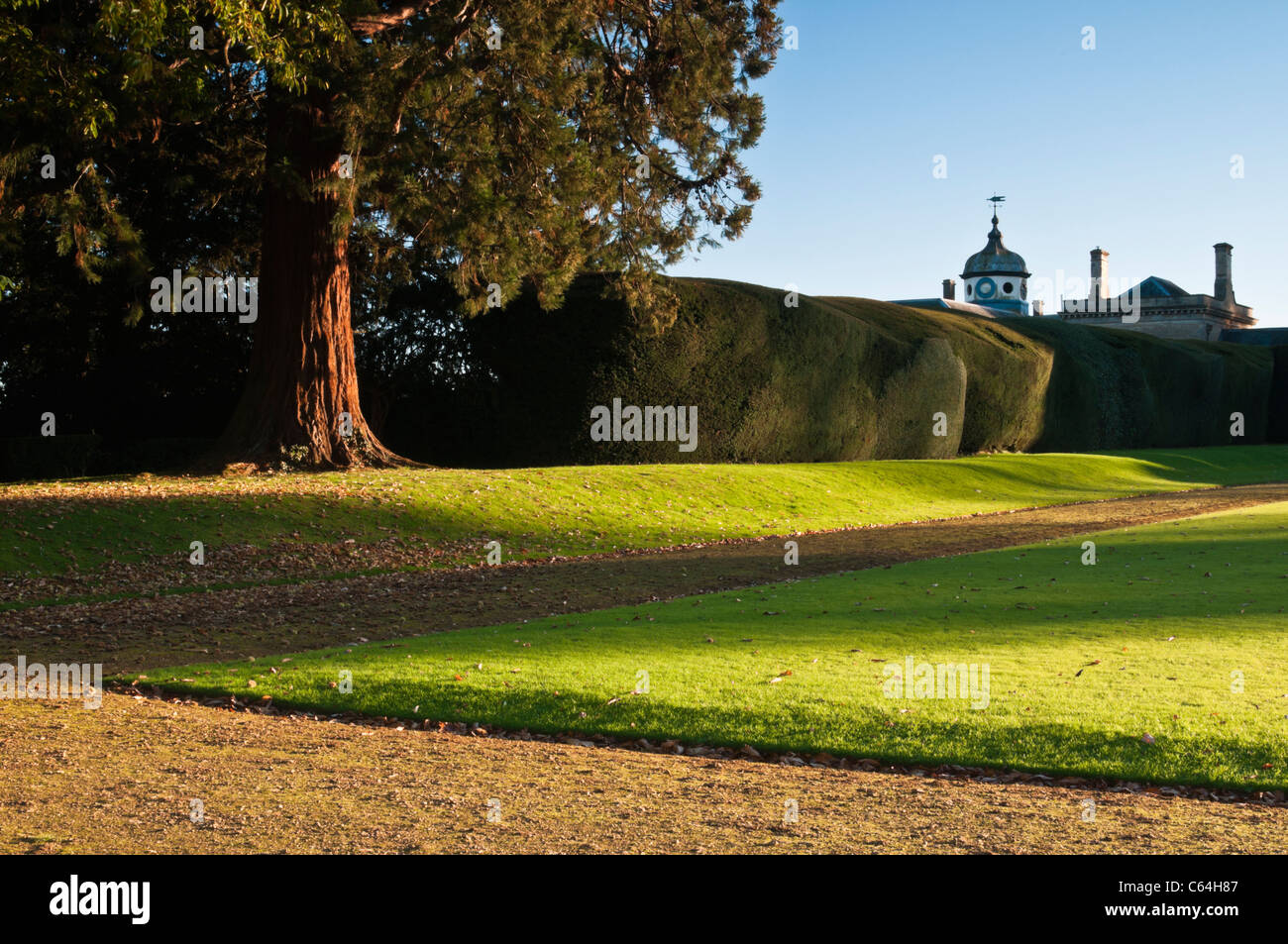 Am späten Nachmittag Sonne fängt eine Ecke von dem Bowling Green (1720) mit der Stableblock über die lange Hecke Rousham House, Oxfordshire, England Stockfoto