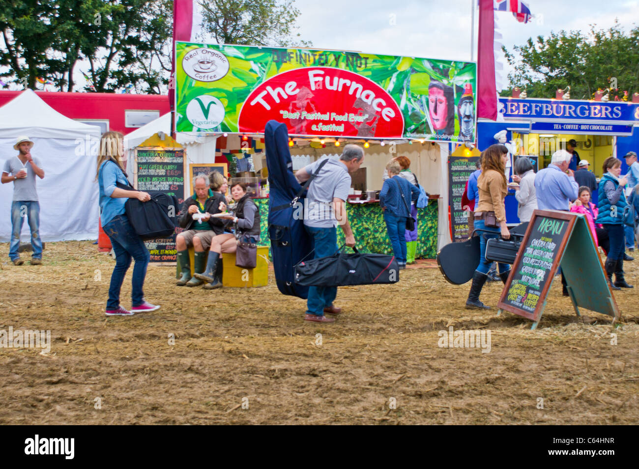 Band-Mitglieder tragen ihre Instrumente über den Schlamm auf dem Wickham Festival August 2011 Stockfoto
