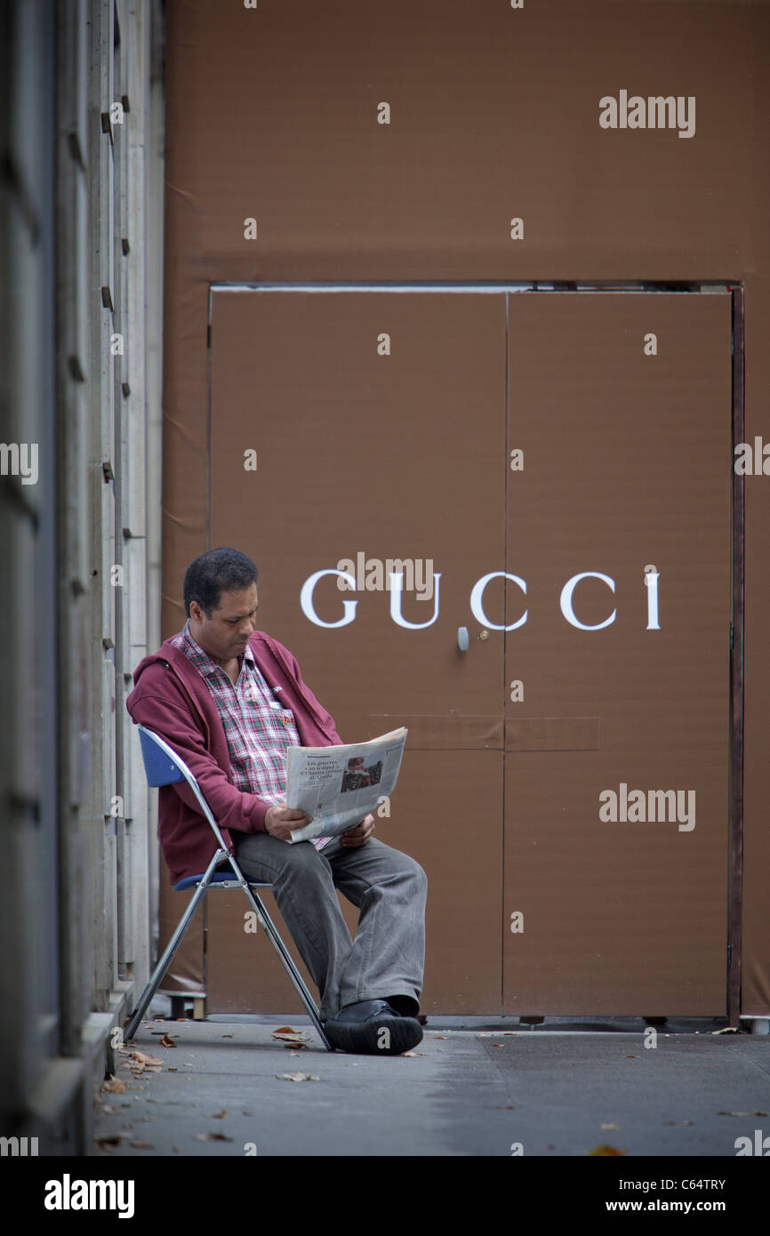 Ein Bauarbeiter nimmt eine Auszeit vom Bau Gucci Store in Paris und liest eine Zeitung Stockfoto