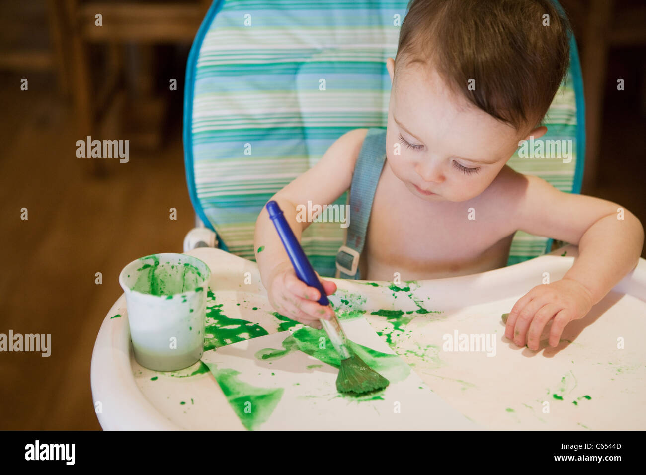 Baby Junge sitzen im Hochstuhl Malerei Bild Stockfoto