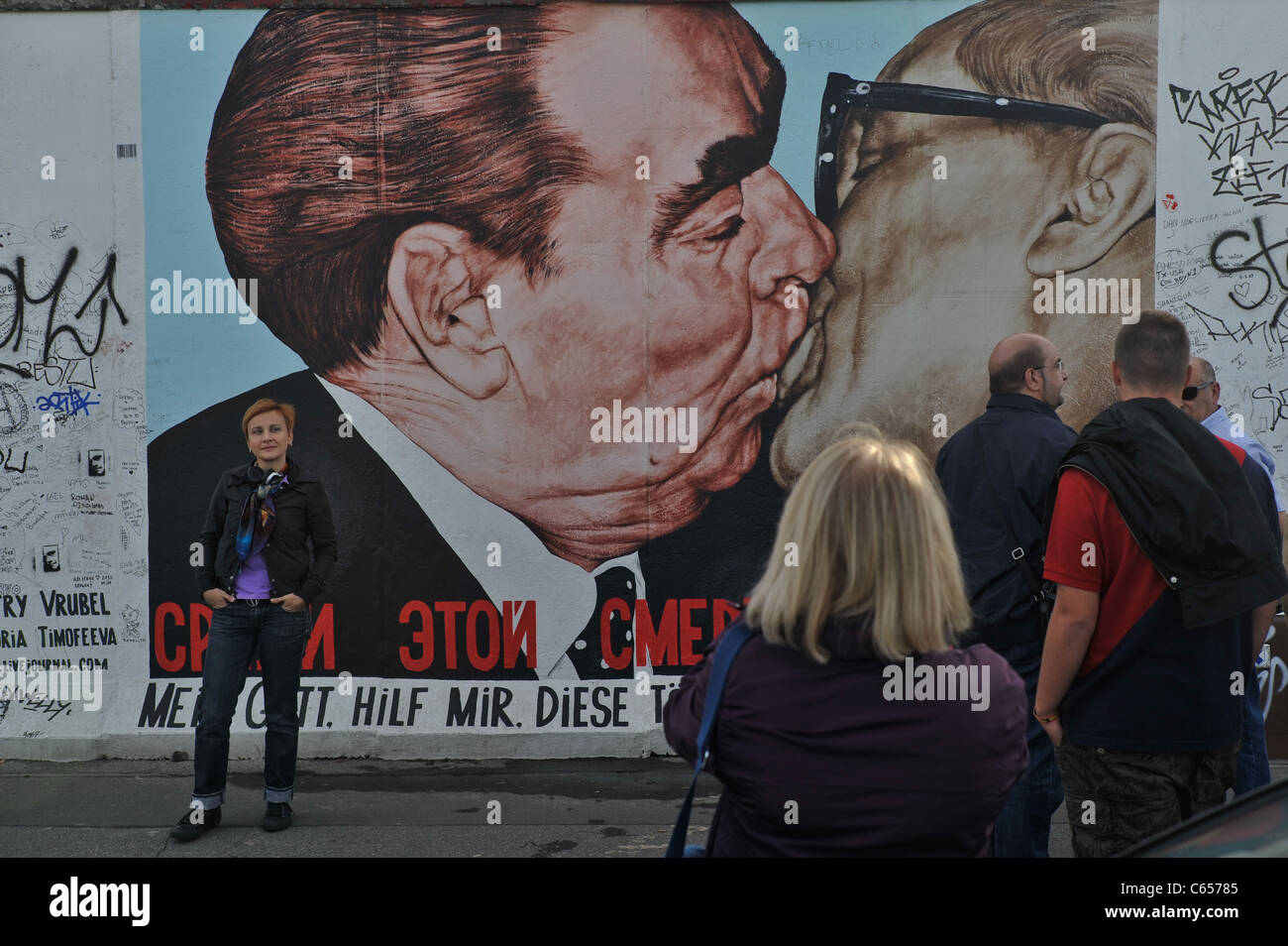 Touristen vor berühmten Wandgemälde von Breschnew Honecker auf der Berliner Mauer. Stockfoto