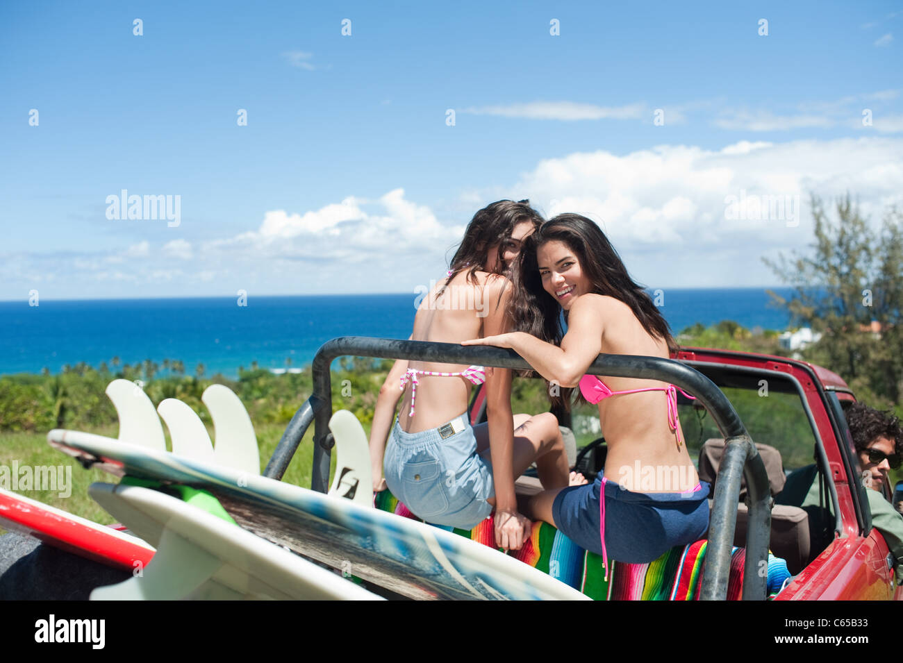 Junge Frauen in Geländewagen mit Surfbrettern Stockfoto