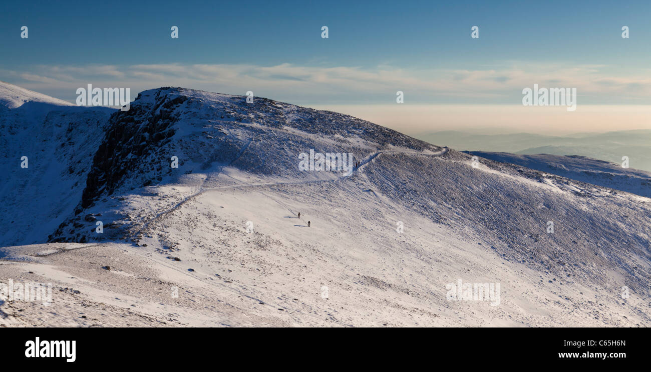 Winterwanderer Abstieg einen schneebedeckten Nethermost Hecht vor dem letzten Licht. Seenplatte, Cumbria, UK Stockfoto