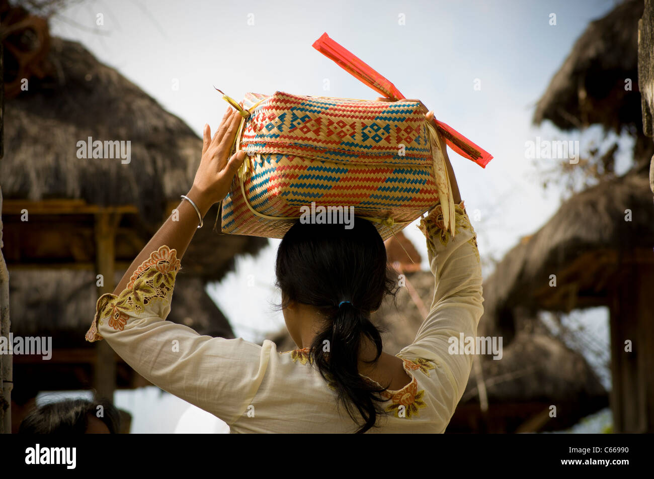 Rückansicht einer balinesischen Frau, die religiöse Opfergaben in einem traditionellen Korb zu einem Hindu-Tempel auf ihrem Kopf trug Stockfoto