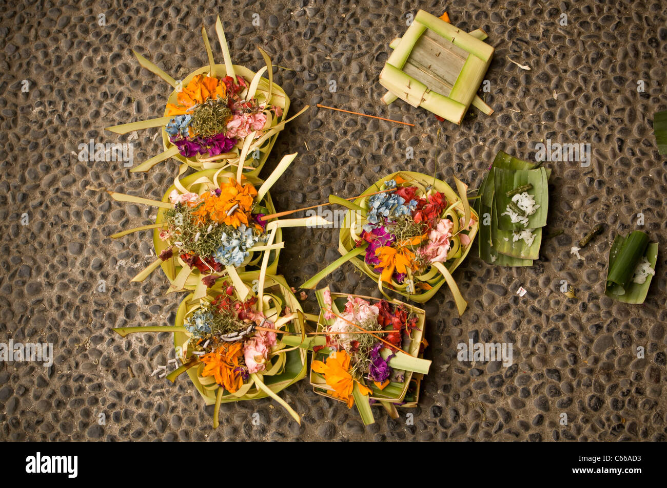 Flache Aufnahme von Canang Sari - tägliches balinesisches Hindu-Angebot, um der Sang Hyang Widhi Wasa zu danken, auf einem Bürgersteig in Kaution Stockfoto