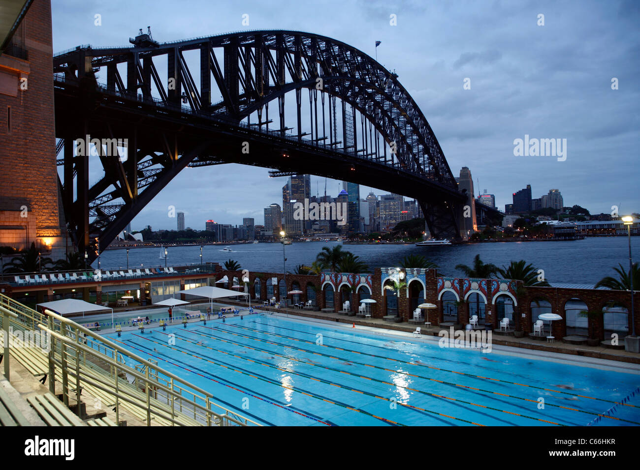 Die Olympia-Schwimmhalle in North Sydney, zeigt die Harbour Bridge mit der Stadt hinter - am frühen Abend Stockfoto