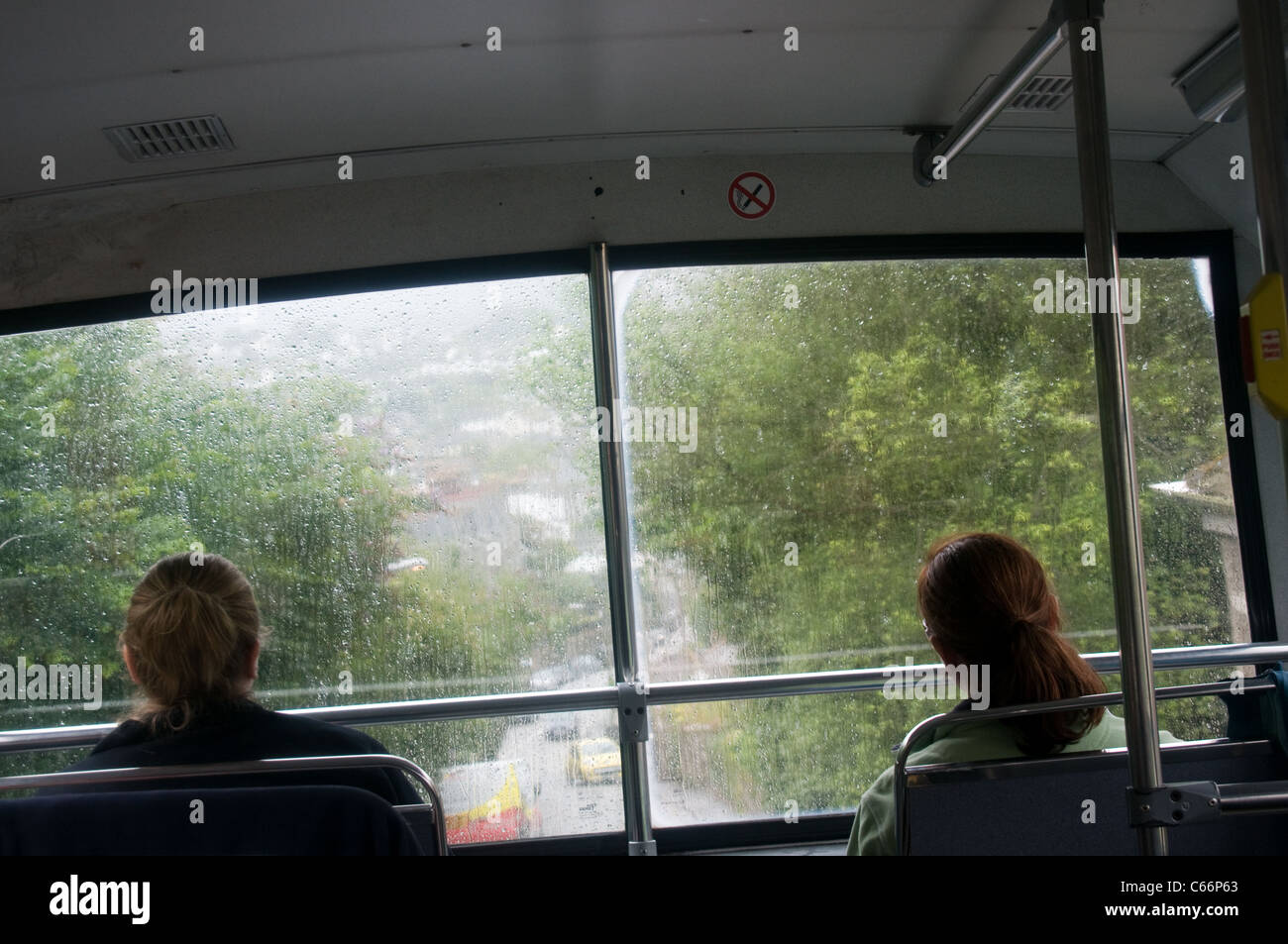 Zwei Passagiere genießen Sie die Aussicht vom obersten Deck ein Doppeldecker an einem verregneten Tag, Penzance, Cornwall nähert Stockfoto