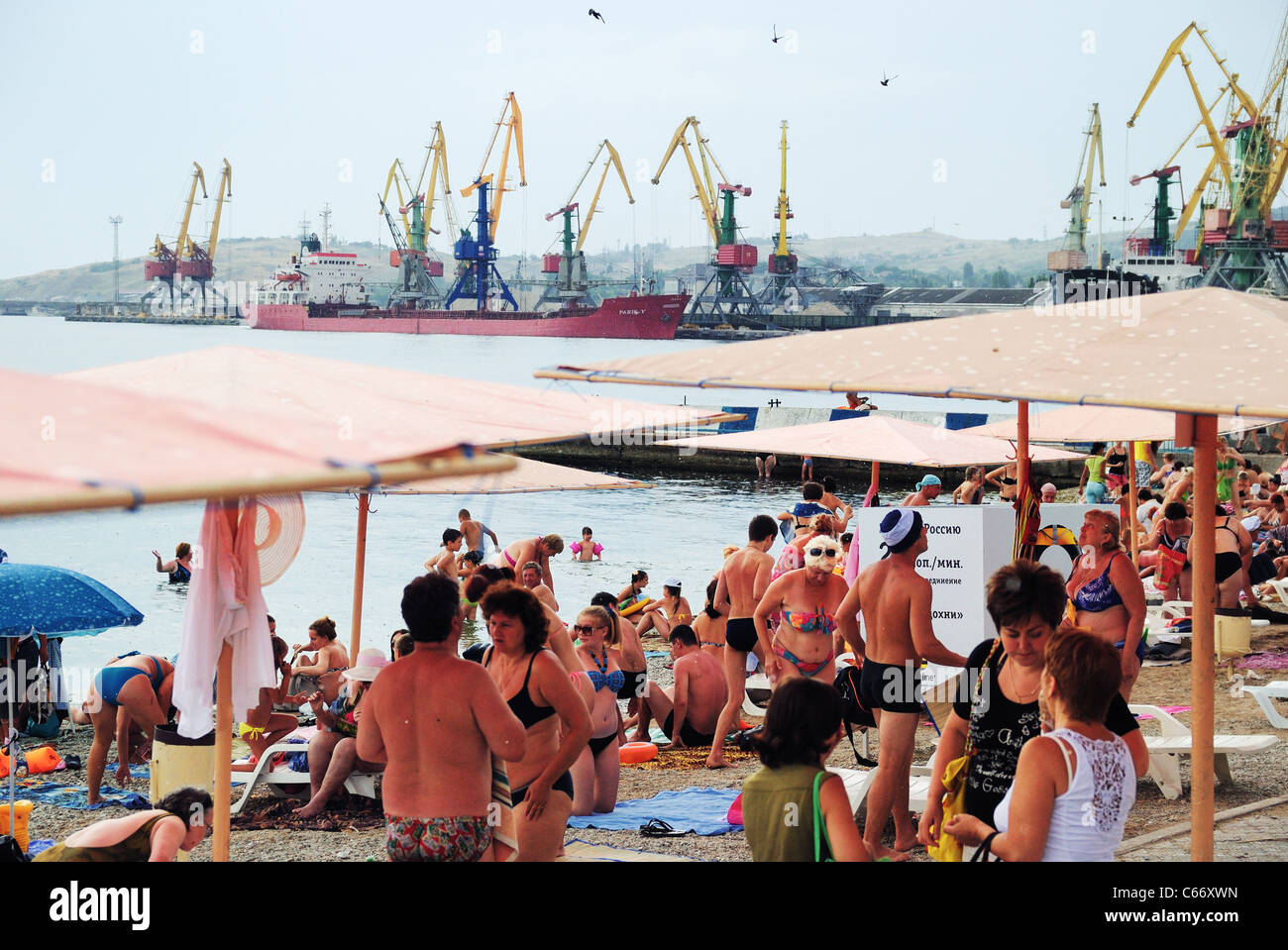 Strand-Szene mit Dock Kran ragt im Hintergrund, Feodossija, Krim, Ukraine Stockfoto
