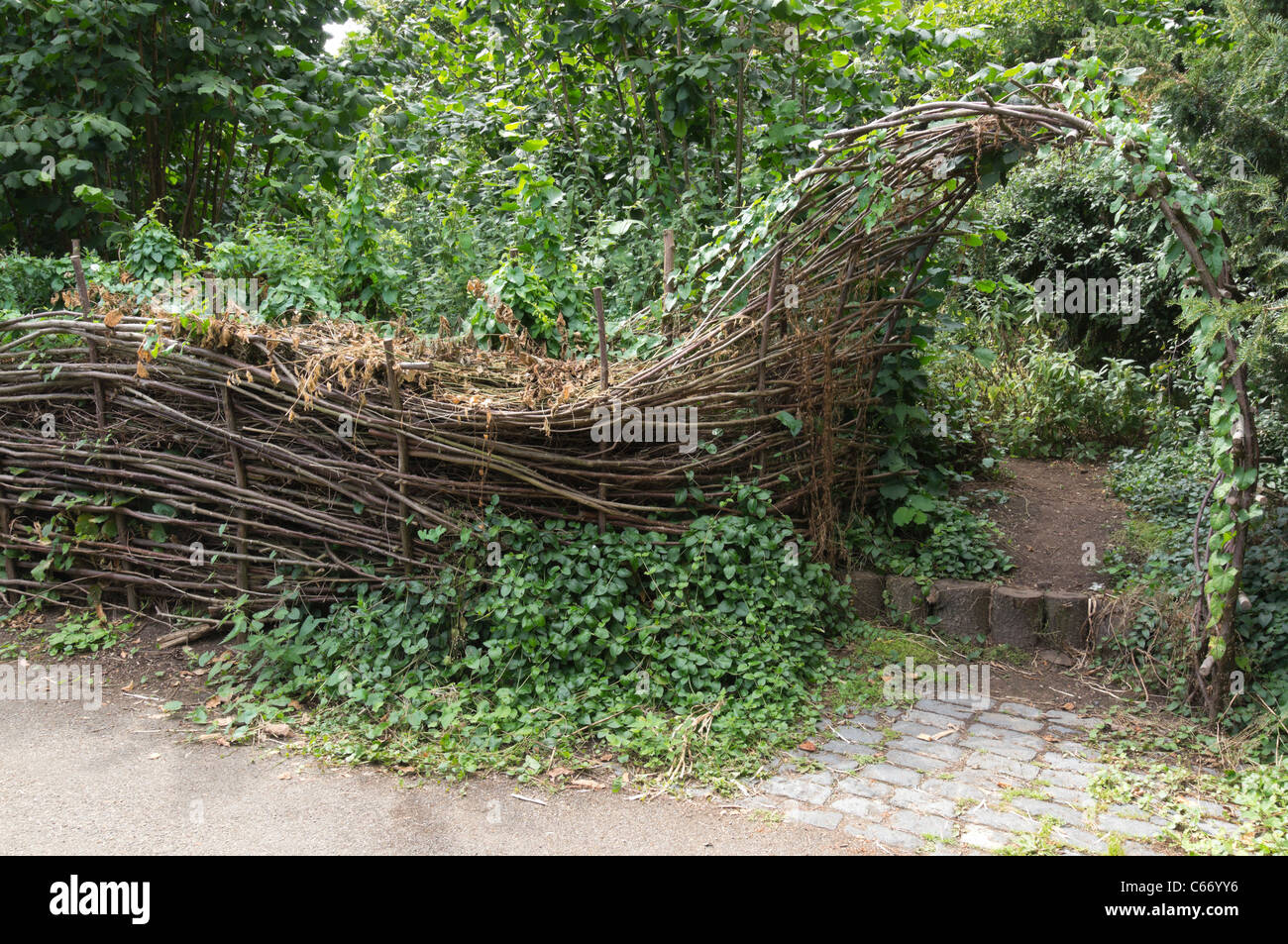 Eine Hecke Barriere aus Stöcken gewebt und gefüllt mit Garten