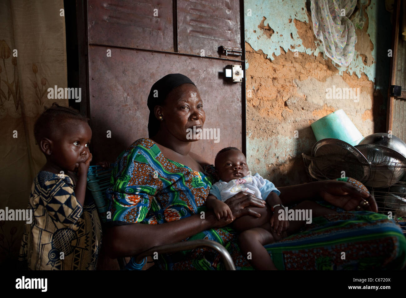 Eine Mutter sitzt in ihrem Hause mit ihren kleinen Kindern in einem Slum in Bamako, Mali, Westafrika. Stockfoto