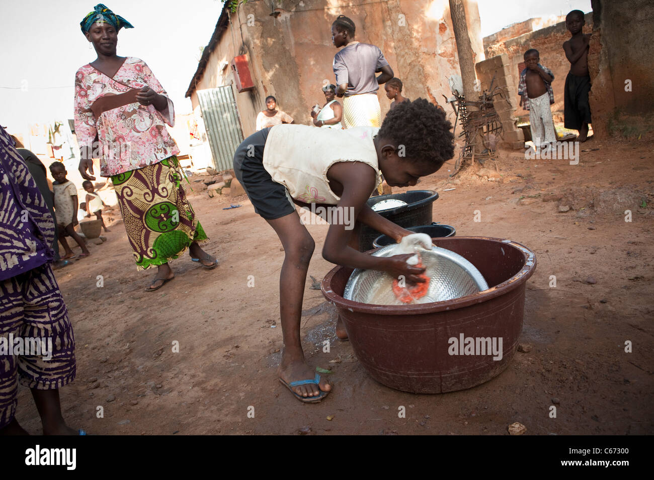 Ein Kind wäscht Gerichte in einem überfüllten einem Slum in Bamako, Mali, Westafrika. Stockfoto