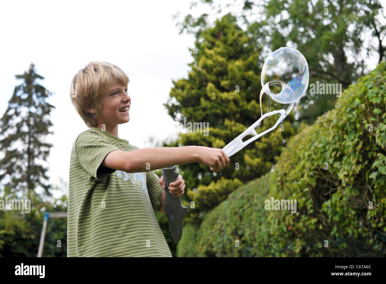 Glücklich und lächelnd blonden Jungen große Seifenblasen im Garten an einem Sommertag Stockfoto