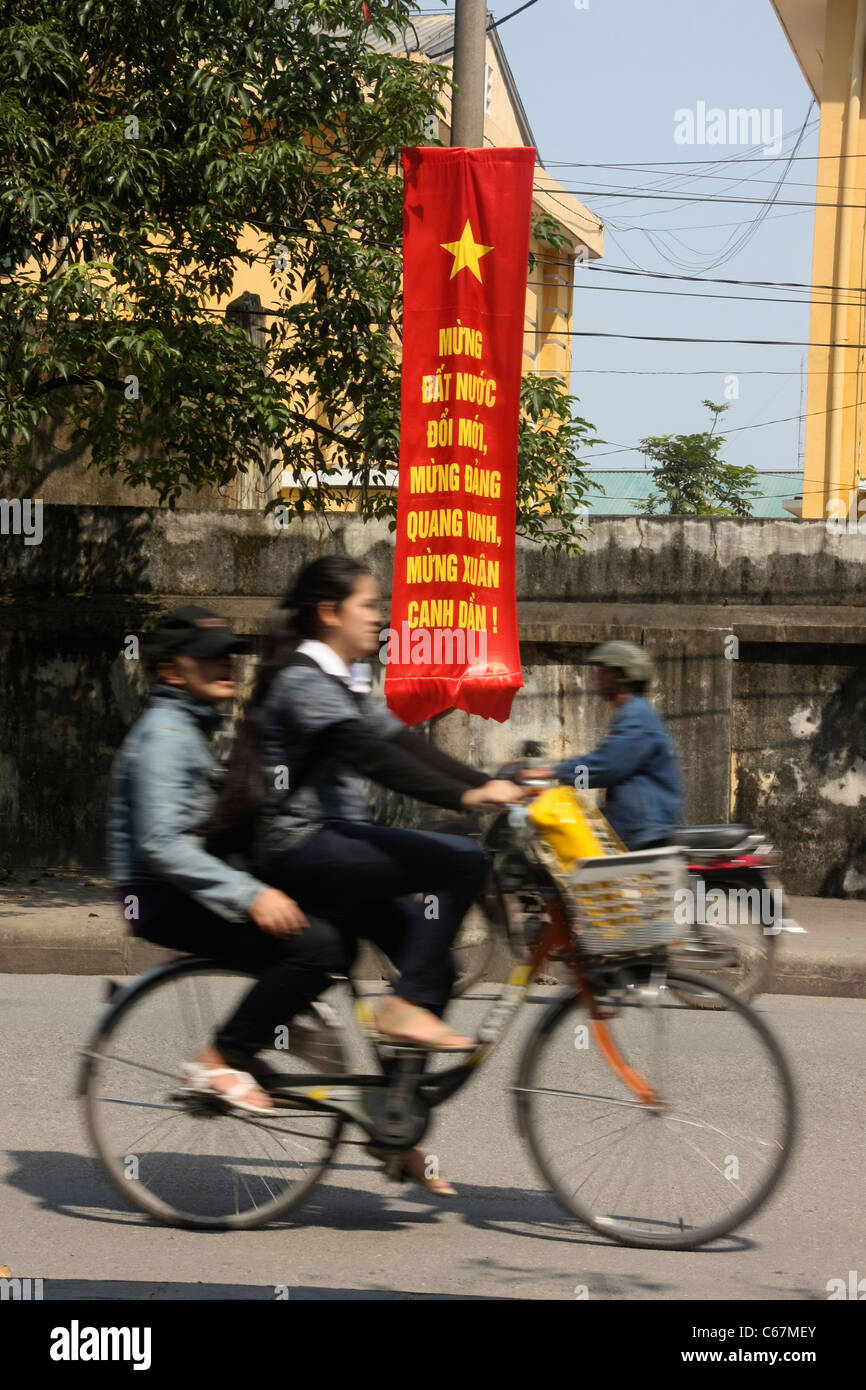 Vietnamesische Radfahrer Geschwindigkeit vorbei kommunistische Banner in Hanoi, Vietnam Stockfoto