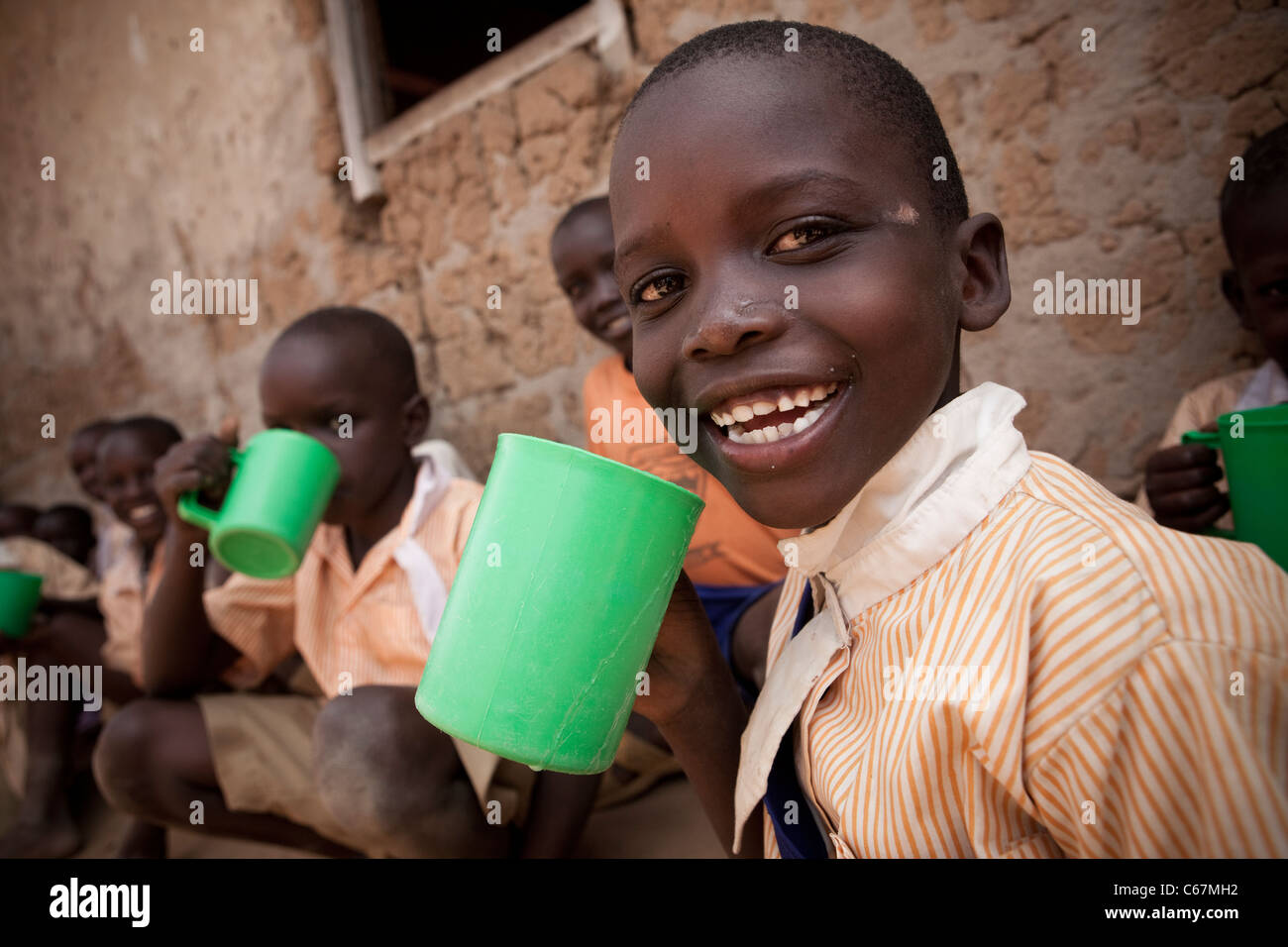 Schuljunge trinkt aus einem Becher in Amuria, Uganda, Ostafrika. Stockfoto