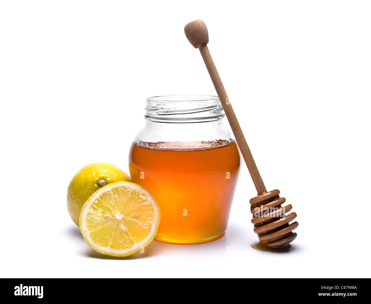 Glas Honig mit einem hölzernen Drizzler und Zitronen. Isoliert auf weißem Hintergrund. Stockfoto